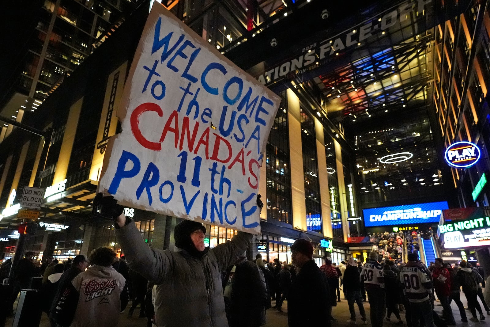 As fans enter the Boston Garden, a man holds a sign on the sidewalk prior to the 4 Nations Face-Off championship hockey game between the United States and Canada, Thursday, Feb. 20, 2025, in Boston. (AP Photo/Charles Krupa)