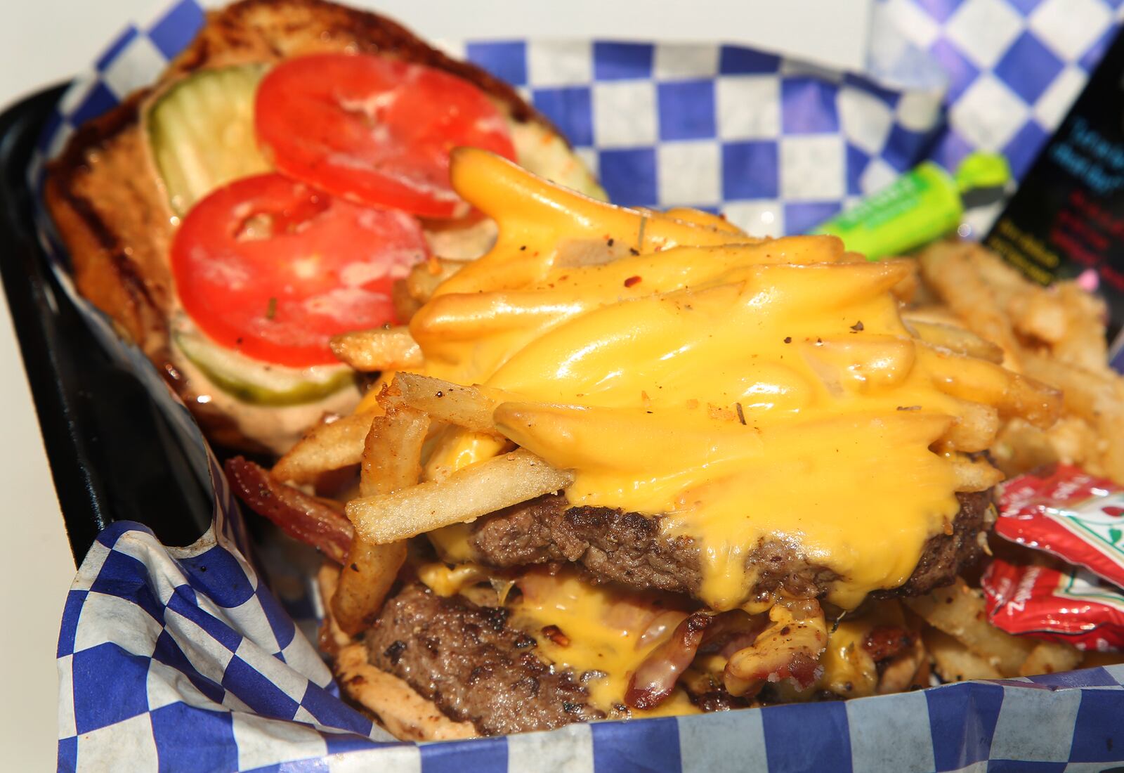 The Rolling Indulgence food truck's Double D's & B burger is two steak patties, bourbon brown sugar bacon, American cheese, Roma tomatos, dill pickles, signature sauce, topped with french fries and served on a toasted garlic brioche bun. LISA POWELL / STAFF