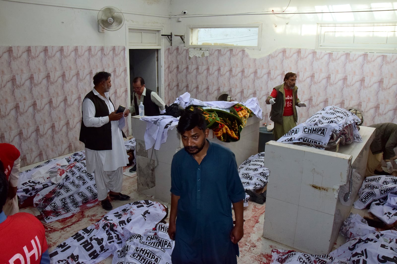 Hospital workers cover the bodies, who were died in a bomb explosion at railway station, at a morgue in Quetta, southwestern Pakistan, Saturday, Nov. 9, 2024. (AP Photo/Arshad Butt)