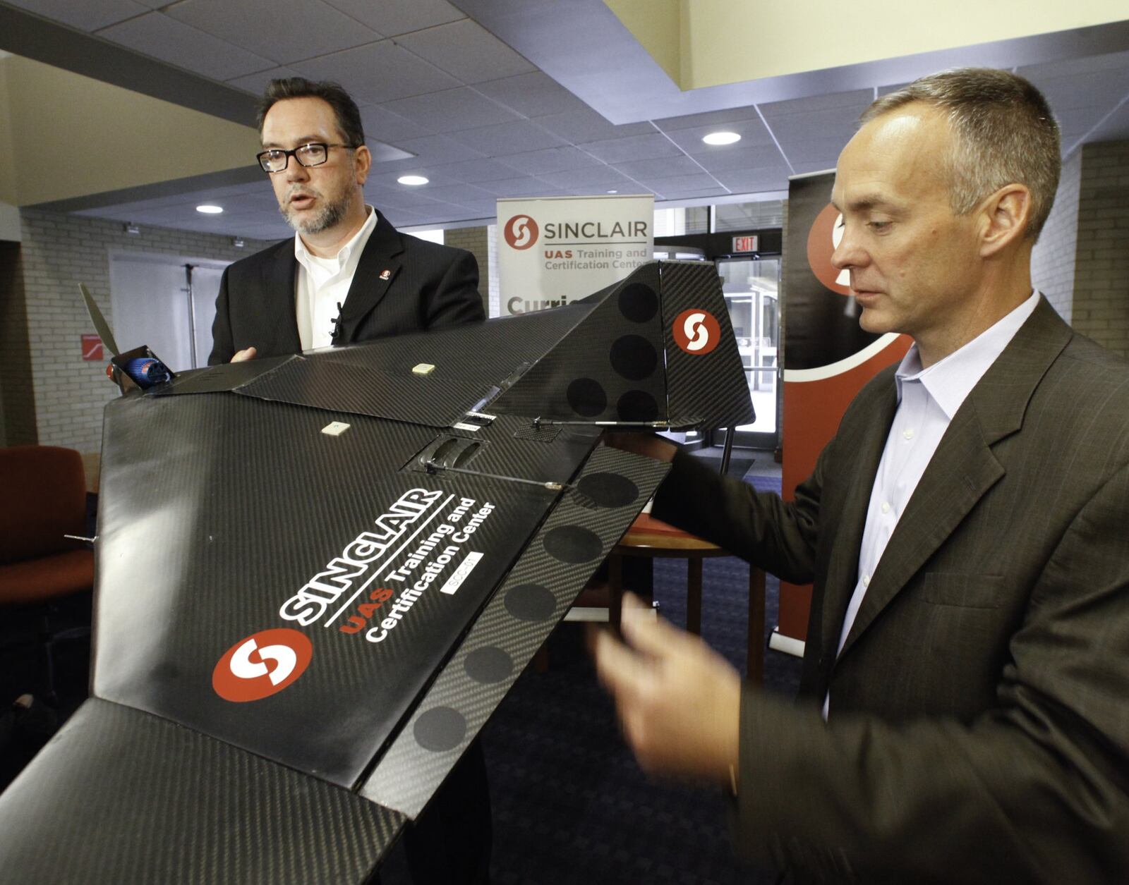 Sinclair Community College President Steve Johnson, left, and Jeff Hoagland, president and CEO of the Dayton Development Coalition, discuss Sinclair’s recently announced $1.4 million investment in an Unmanned Aerial Systems Program. CHRIS STEWART / STAFF