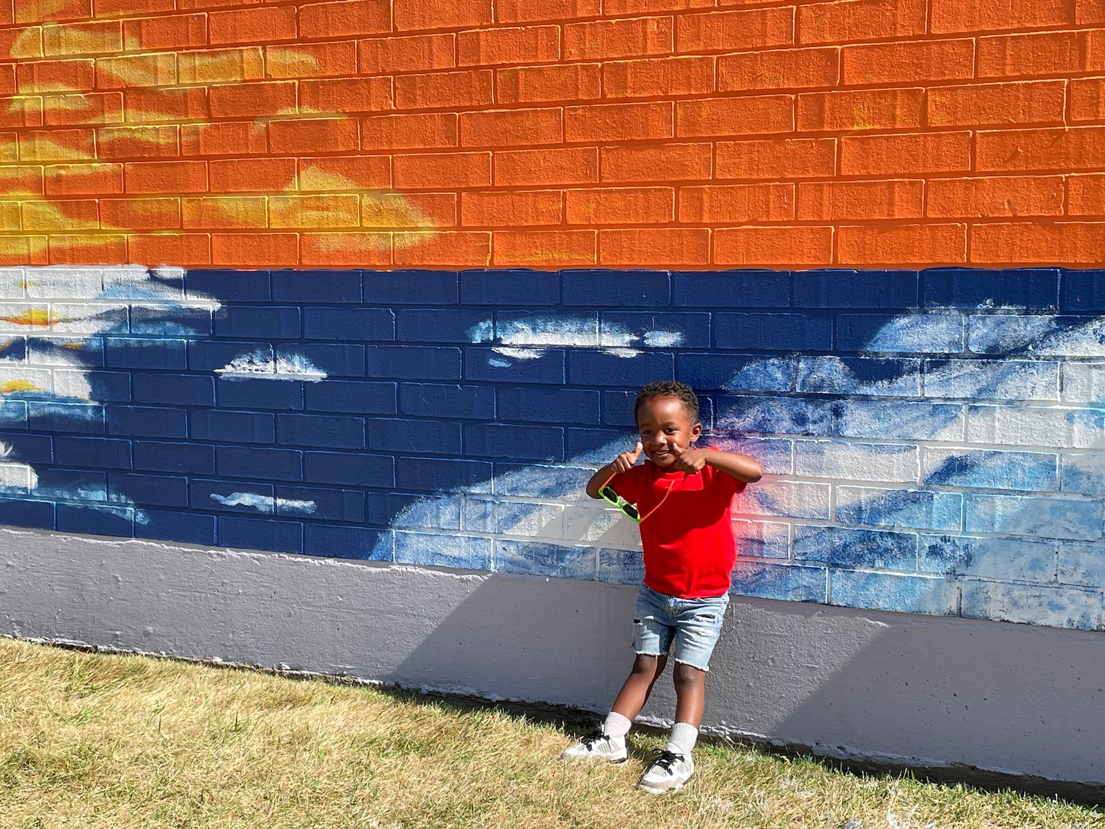 Carter Hill, of Dayton, gives a thumbs up to the new mural on the side of Tuffy Brooks Sporting Goods, 101 South Keowee Street, Dayton. The suicide prevention mural was painted by Montgomery County Prevention Coalition volunteers and graduates of the Dayton Area Chamber of Commerce Leadership Dayton Class of 2024 with the message “Behind Every Dark Cloud, The Sun Will Rise.” A QR code embedded in the mural will direct people to mental health and recovery resources. The mural was completed in late June 2024. SAM WILDOW\STAFF