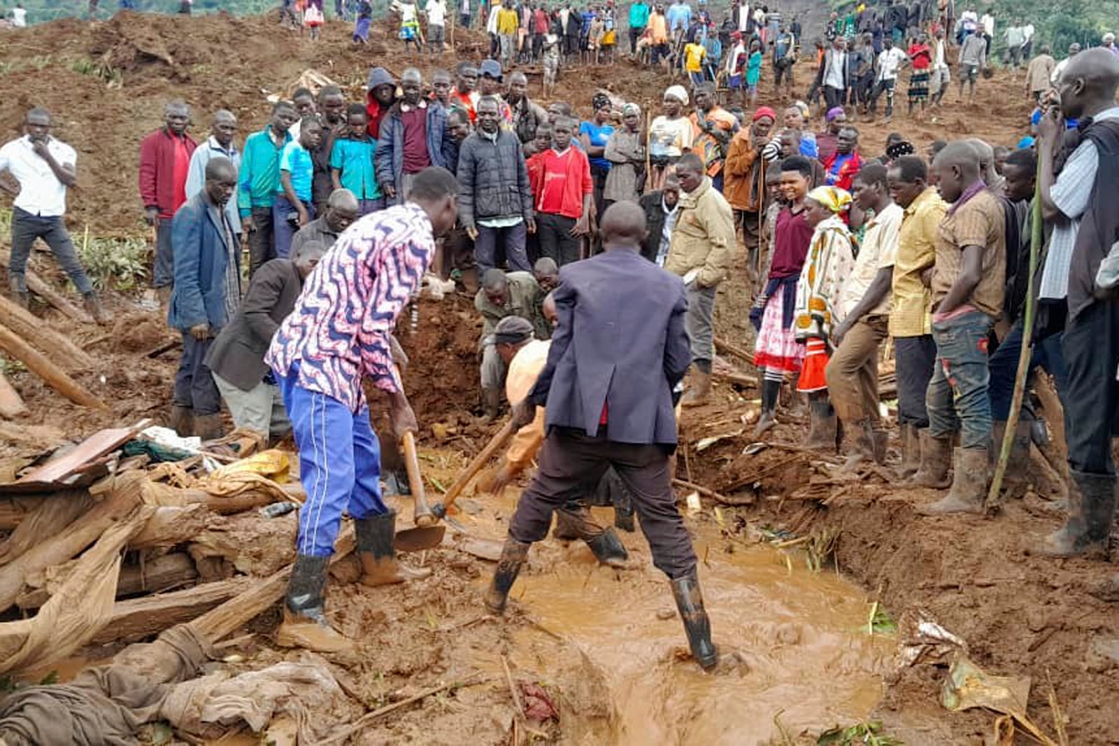 Rescue workers and people search for bodies after landslides following heavy rains buried 40 homes in the mountainous district of Bulambuli, eastern Uganda, Thursday, Nov. 28. 2024. (AP Photo/Jean Watala)