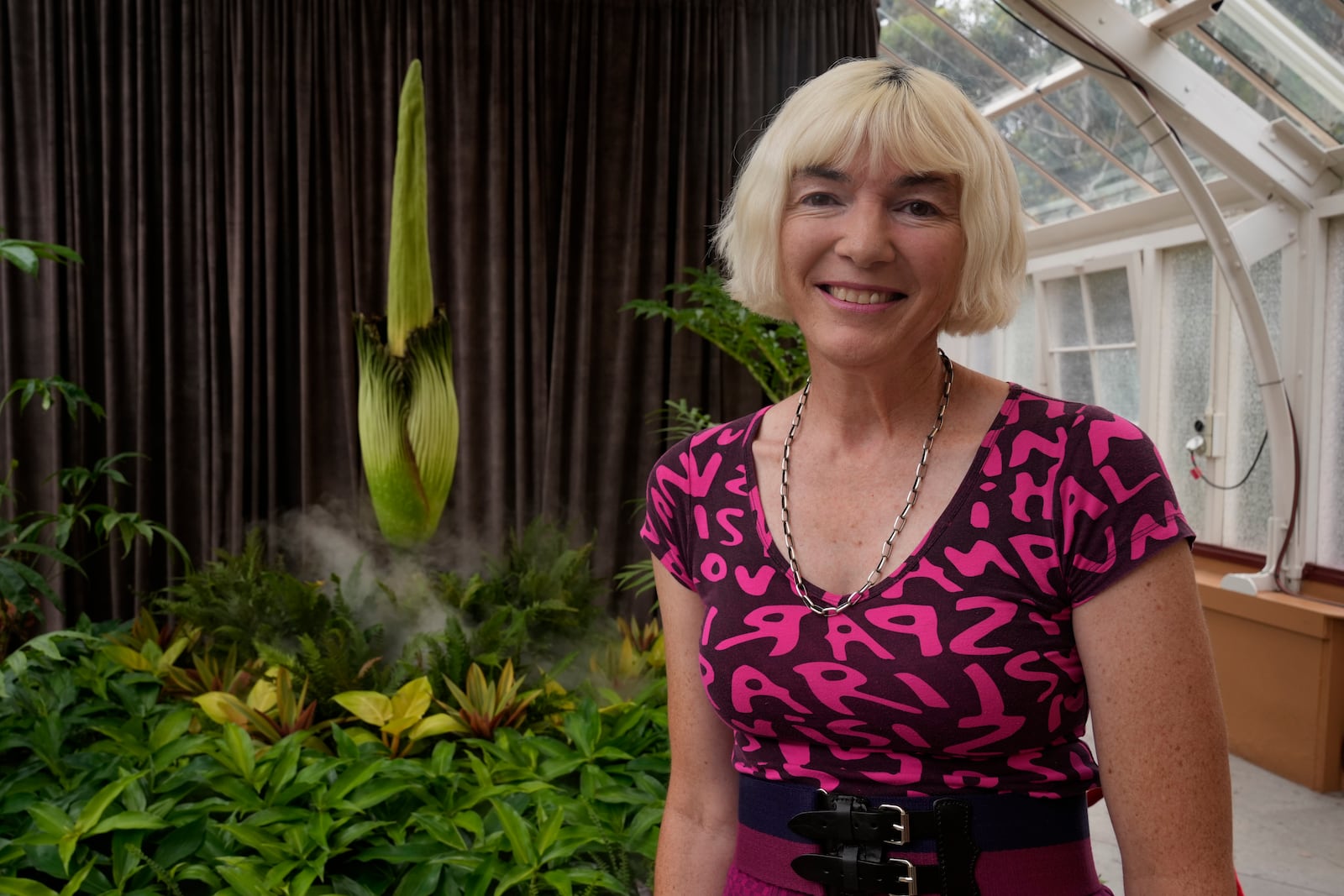 Sophie Daniel poses for a photo next to an endangered plant known as the "corpse flower" for its putrid stink, at the Royal Botanical Gardens in Sydney, Australia, Thursday, Jan. 23, 2025. (AP Photo/Rick Rycroft)