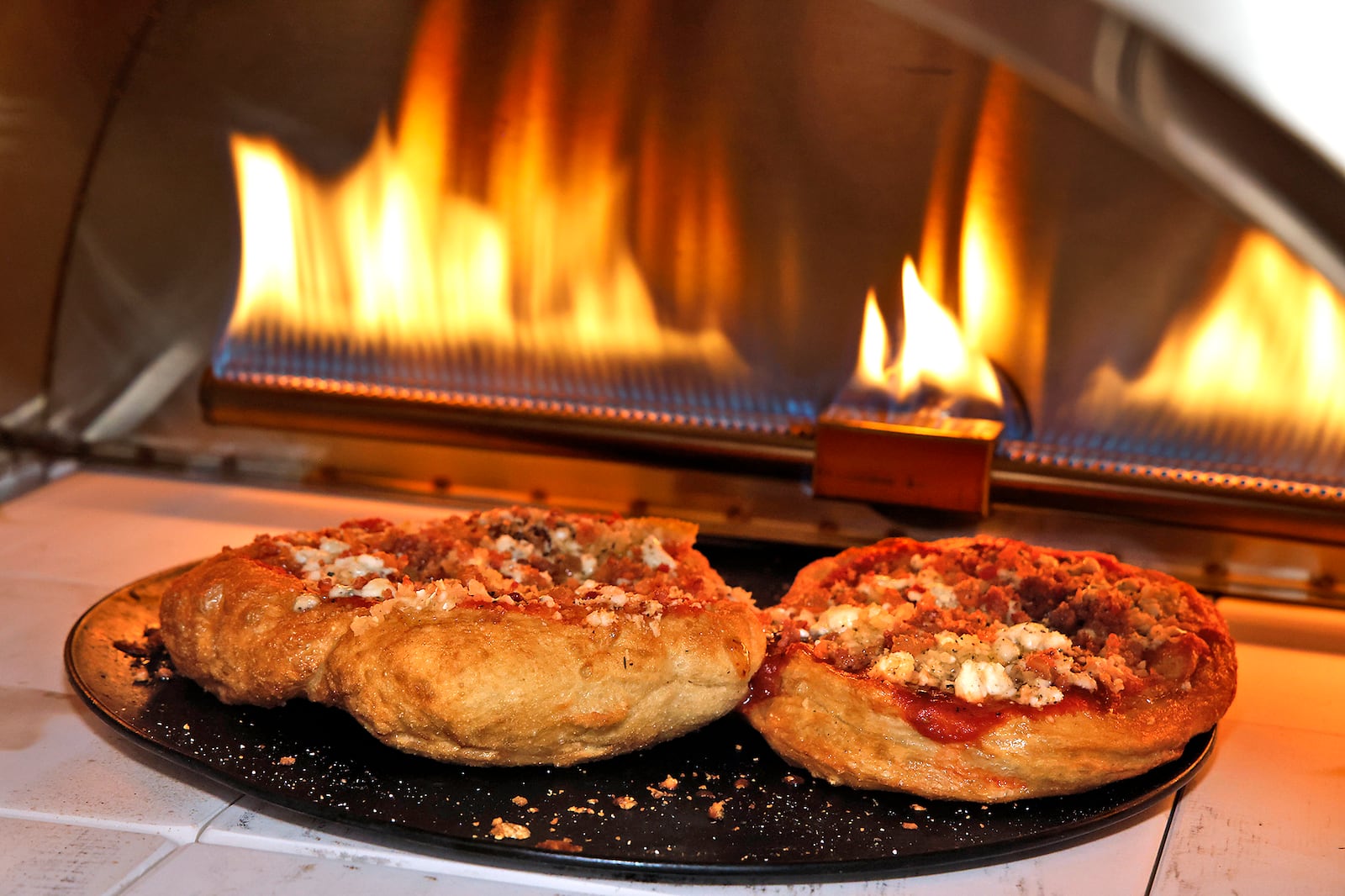 Two fig, bacon, onion and gorgonzola fried pizzas in the pizza oven at Eatly Thursday, May 23, 2024. BILL LACKEY/STAFF