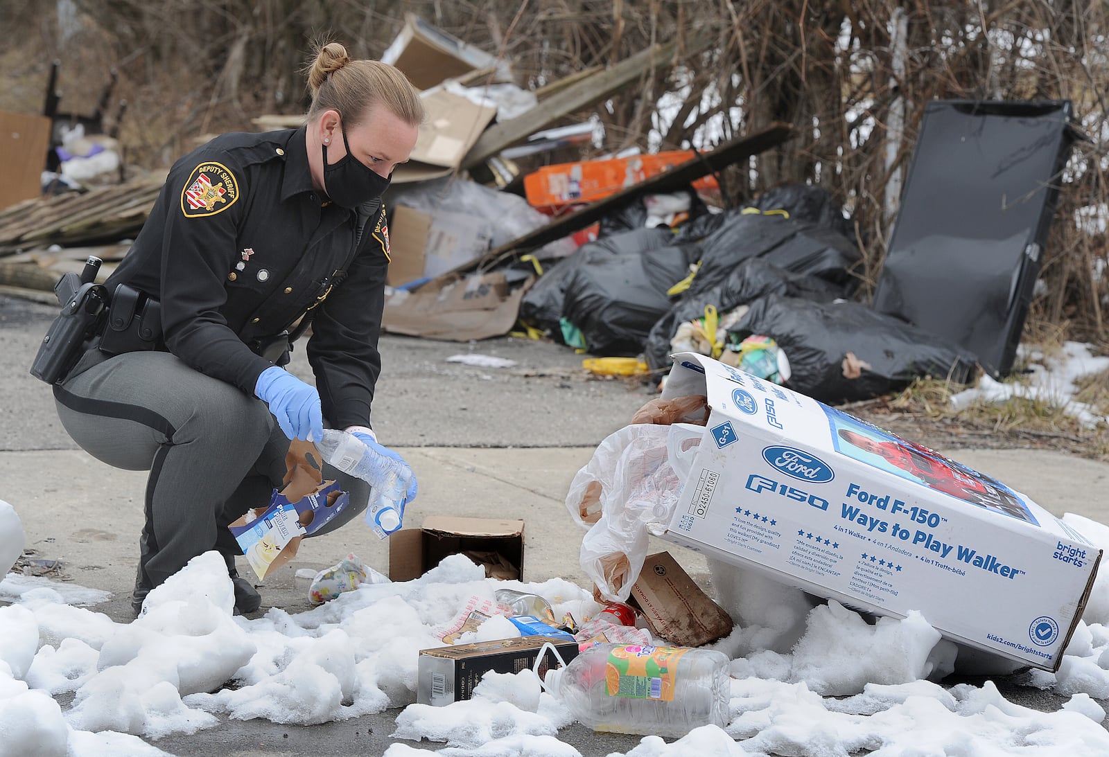 Montgomery County Environmental Enforcement Deputy, Robbie Jackson, looks through trash at a illegal dump site on Bender Ave. Thursday, Feb. 4, 2021. MARSHALL GORBY\STAFF