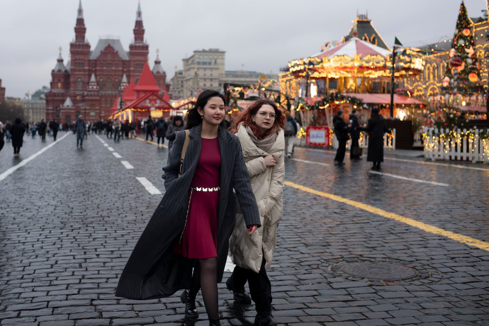 Two young women walk through Red Square in Moscow, Russia, on Wednesday, Jan. 29, 2025, during an unusually warm spell with temperatures of 5 degrees Celsius (41 degrees Fahrenheit). (AP Photo/Alexander Zemlianichenko)