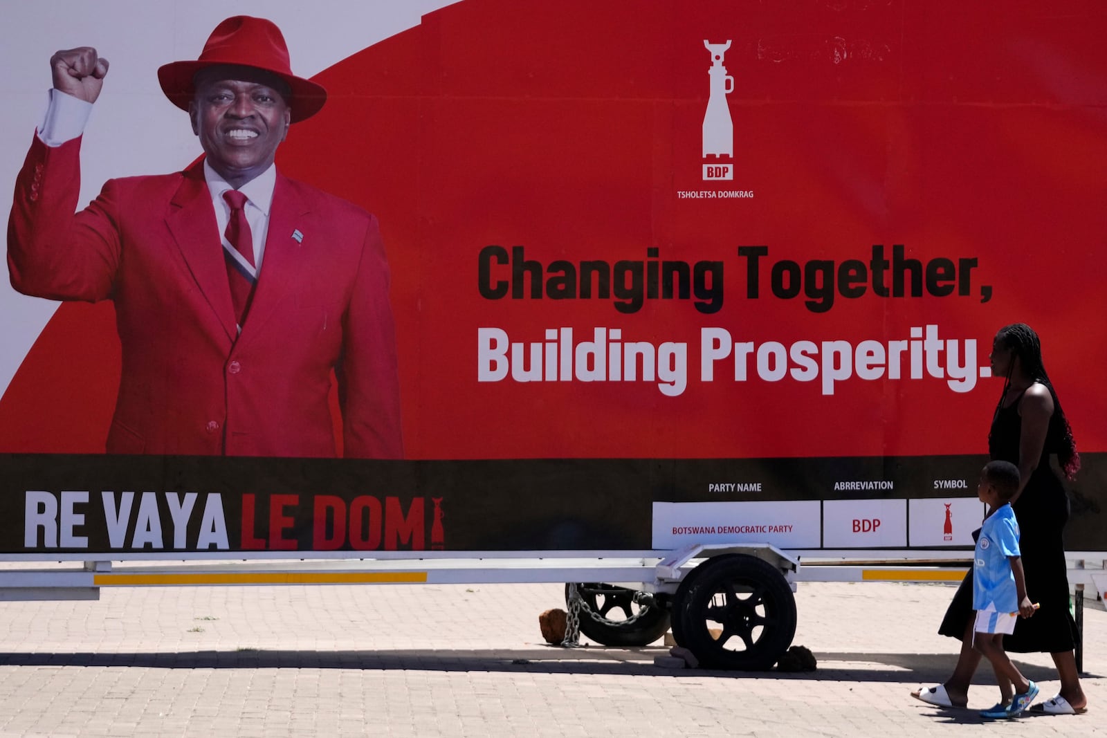 A woman and a child passes an election poster of ruling party Botswana Democratic Party president Mokgweetsi Masisi in Gaborone, Botswana, Tuesday, Oct. 29, 2024. (AP Photo/Themba Hadebe)