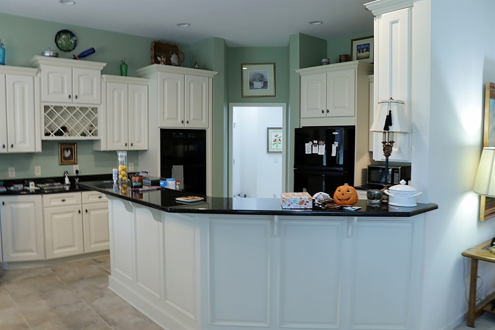 Matching the great room’s fireplace surround, black granite countertops complement white cabinetry throughout the kitchen. The kitchen comes equipped with a cooktop, wall ovens and dishwasher. Hanging cabinetry includes a bottle rack and has under cabinet lighting. CONTRIBUTED PHOTO BY KATHY TYLER