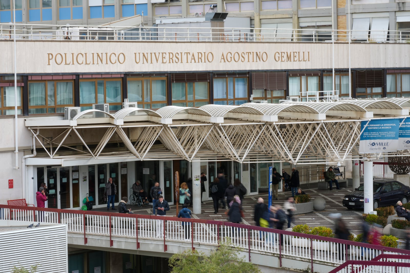 People arrive and leave the Agostino Gemelli Polyclinic in Rome, Friday, Feb. 14, 2025, where Pope Francis has been hospitalised to undergo a necessary diagnostic tests and to continue his ongoing treatment for bronchitis. (AP Photo/Andrew Medichini)