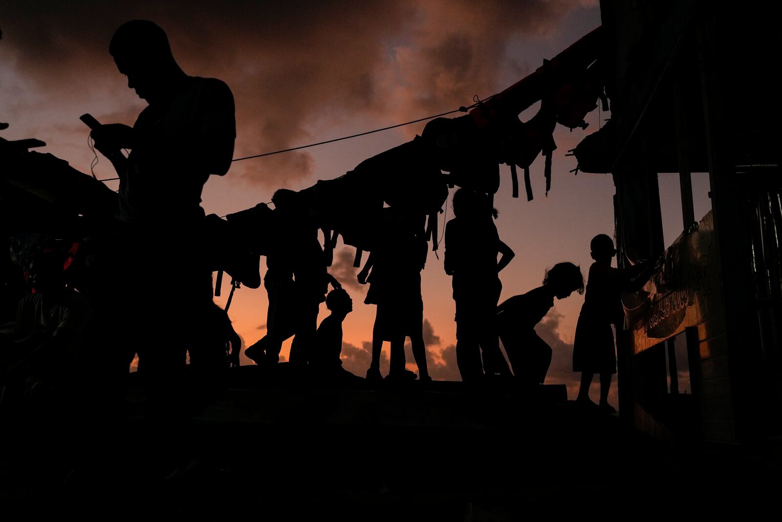 Migrants wind down during sunset on Gardi Sugdub Island, on Panama's Caribbean coast, Sunday, Feb. 23, 2025, where they will overnight before attempting to board boats to Colombia the following day after turning back from southern Mexico, abandoning hopes of reaching the U.S. amid President Trump's crackdown on migration. (AP Photo/Matias Delacroix)