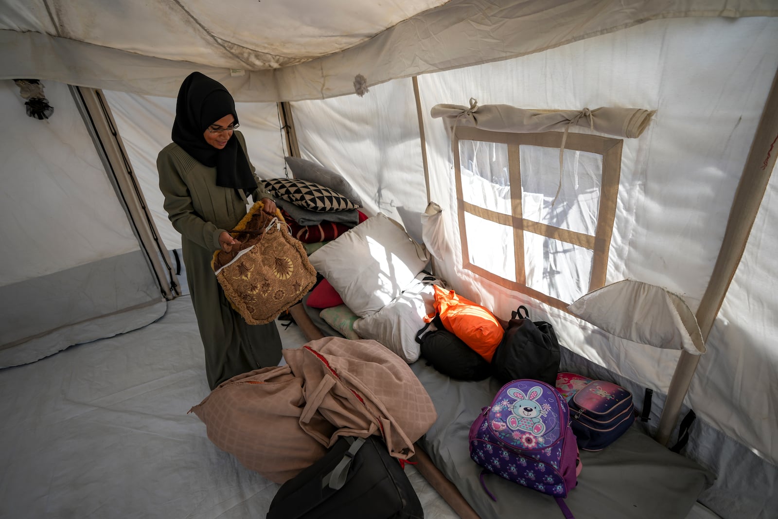 Majida Abu Jarad packs belongings as she prepares to go back to the family's home in the north, at a camp for displaced Palestinians in the Muwasi area, southern Gaza Strip, Saturday, Jan. 18, 2025. (AP Photo/Abdel Kareem Hana)