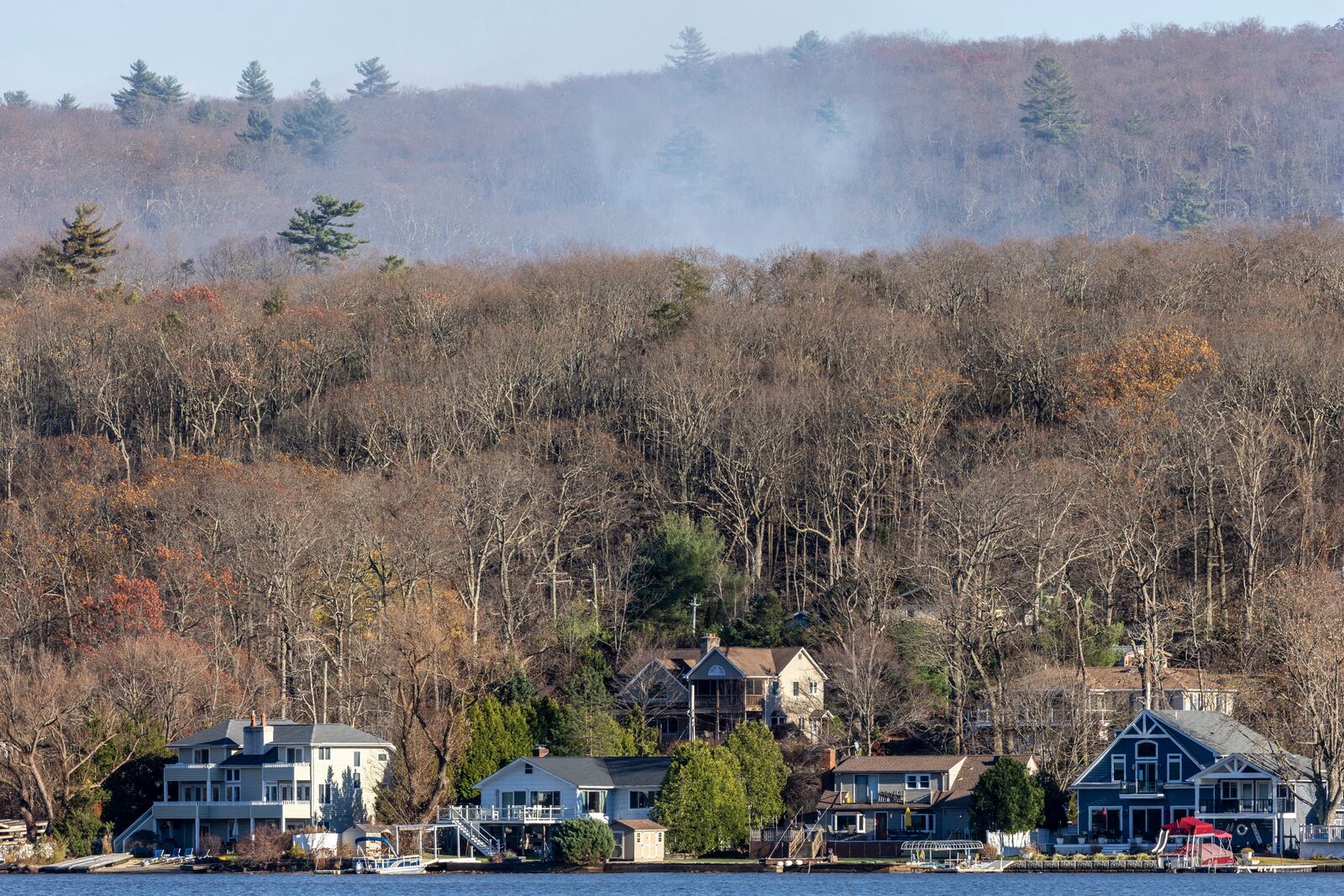 Smoke rises from a wildfire behind a row of lakefront properties in the town of Awosting, as seen from across Greenwood Lake, Lakeside, N.J., Monday, Nov. 11, 2024. (AP Photo/Stefan Jeremiah)