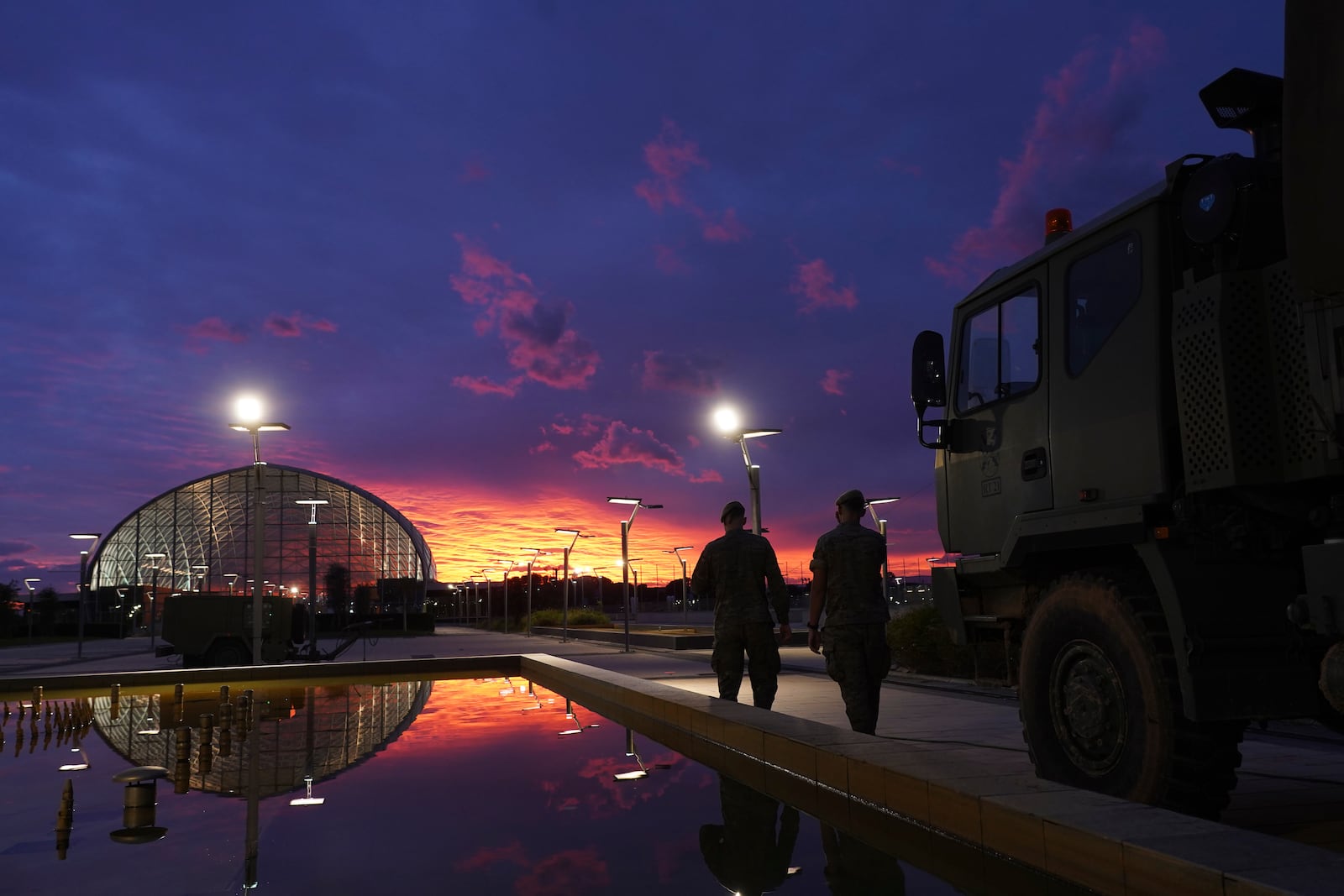 Soldiers walk by a military truck at sunset in Valencia after floods left hundreds dead or missing in the Valencia region in Spain, Tuesday, Nov. 12, 2024. (AP Photo/Alberto Saiz)