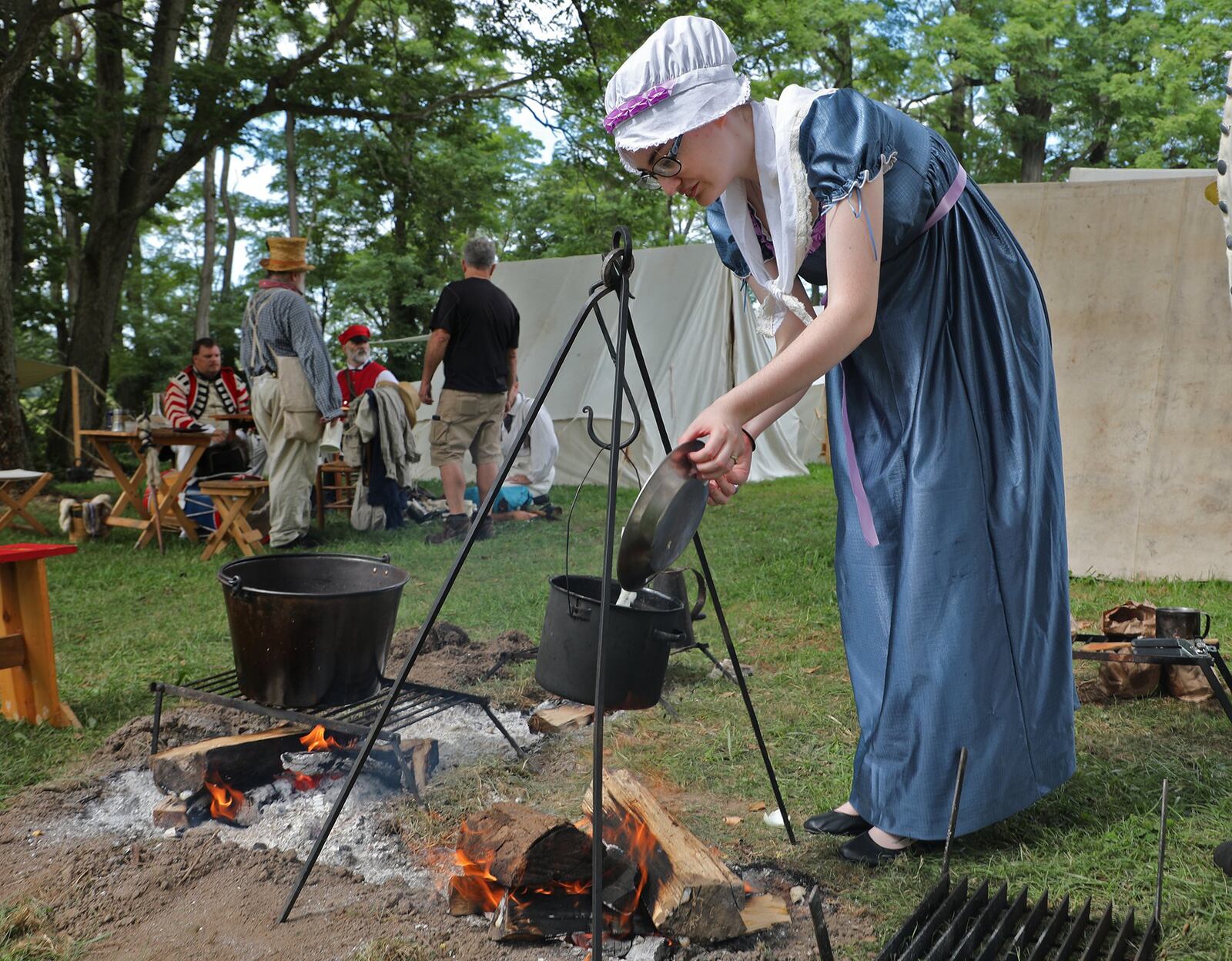 Vannessa Chance cooks over an open fire Saturday at the military encampment at last year’s Fair at New Boston. BILL LACKEY/STAFF