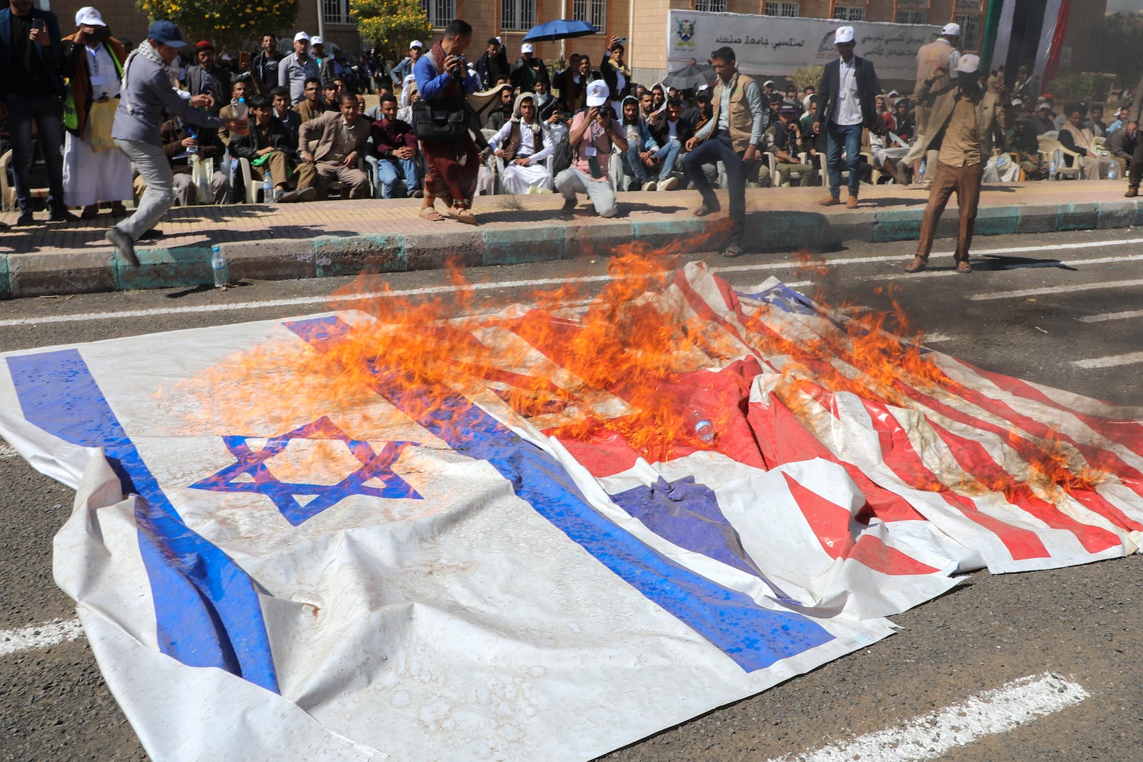 Yemeni graduates of fighting courses organised by Houthi group, burn Israeli British and American flags in support of Gaza during a parade, in Sanaa, Yemen, Wednesday, Dec. 4, 2024. (AP Photo/Osamah Abdulrahman)