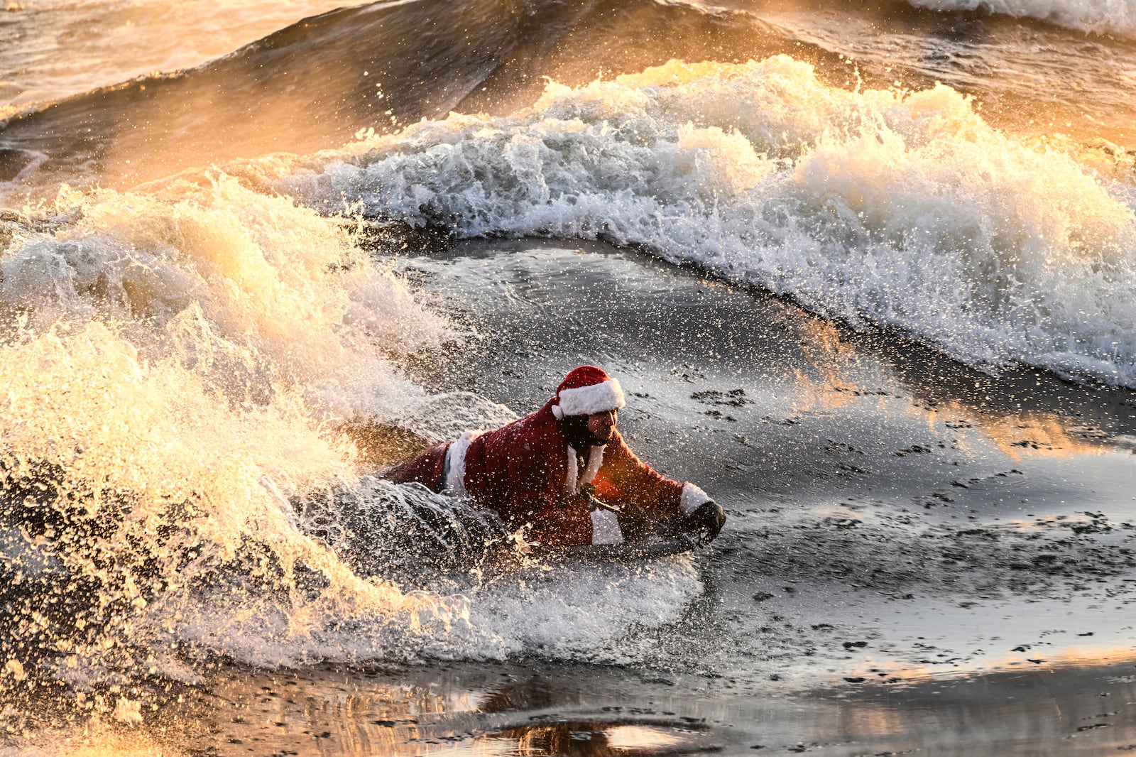 Carlos Hebert Plante, who boogie boards daily, dressed as Santa Claus hits the St-Lawrence River amid an air temperature of -14 degrees Celsius on Christmas Day, in Montreal, Wednesday, Dec. 25, 2024. (Bernard Brault /The Canadian Press via AP)