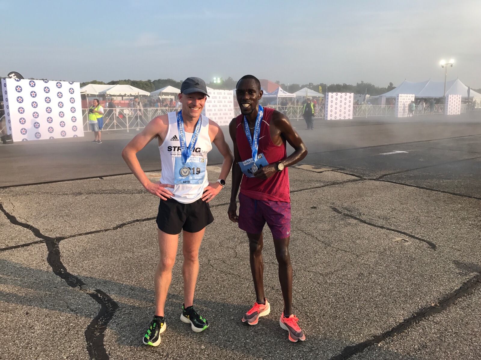 John Mascari (left) after winning half marathon Saturday at Wright Patterson Air Force Base poses with pacer Paul Chelimo, a two-time U.S. Olympic medal winner. Tom Archdeacon/CONTRIBUTED