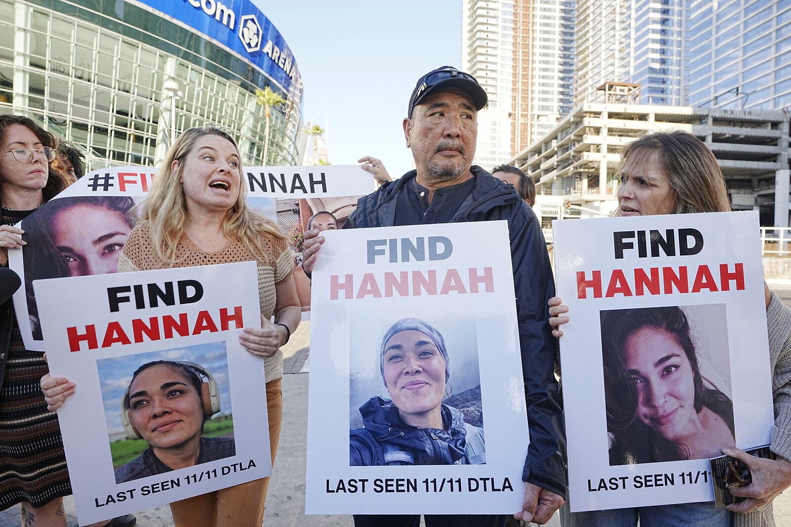 Ryan Kobayashi, center, holds a picture of his missing daughter Hannah Kobayashi outside Crypto.com Arena, Thursday, Nov. 21, 2024 in Los Angeles. (AP Photo/Damian Dovarganes)