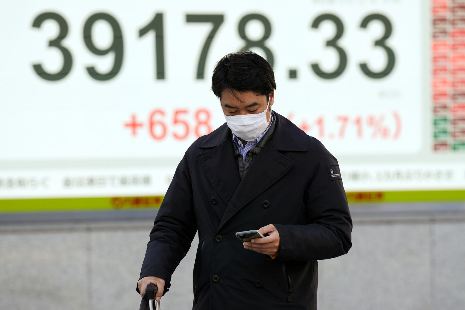 A person walks in front of an electronic stock board showing Japan's Nikkei index at a securities firm Tuesday, Feb. 4, 2025, in Tokyo. (AP Photo/Eugene Hoshiko)