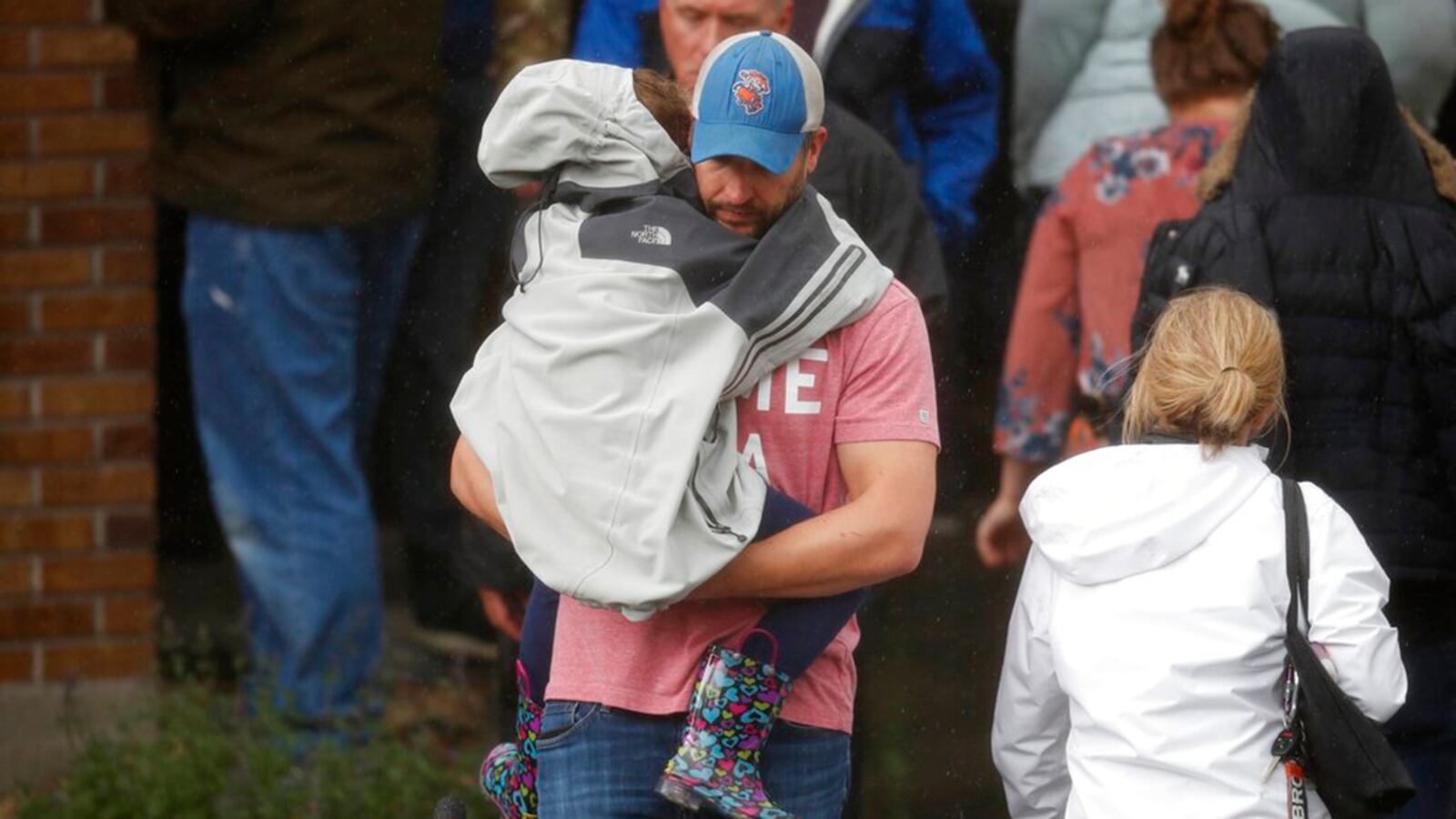 A man carries a child out of a recreation center set up for students to get reunited with their parents after a shooting at a suburban Denver middle school Tuesday, May 7, 2019, in Highlands Ranch, Colorado.