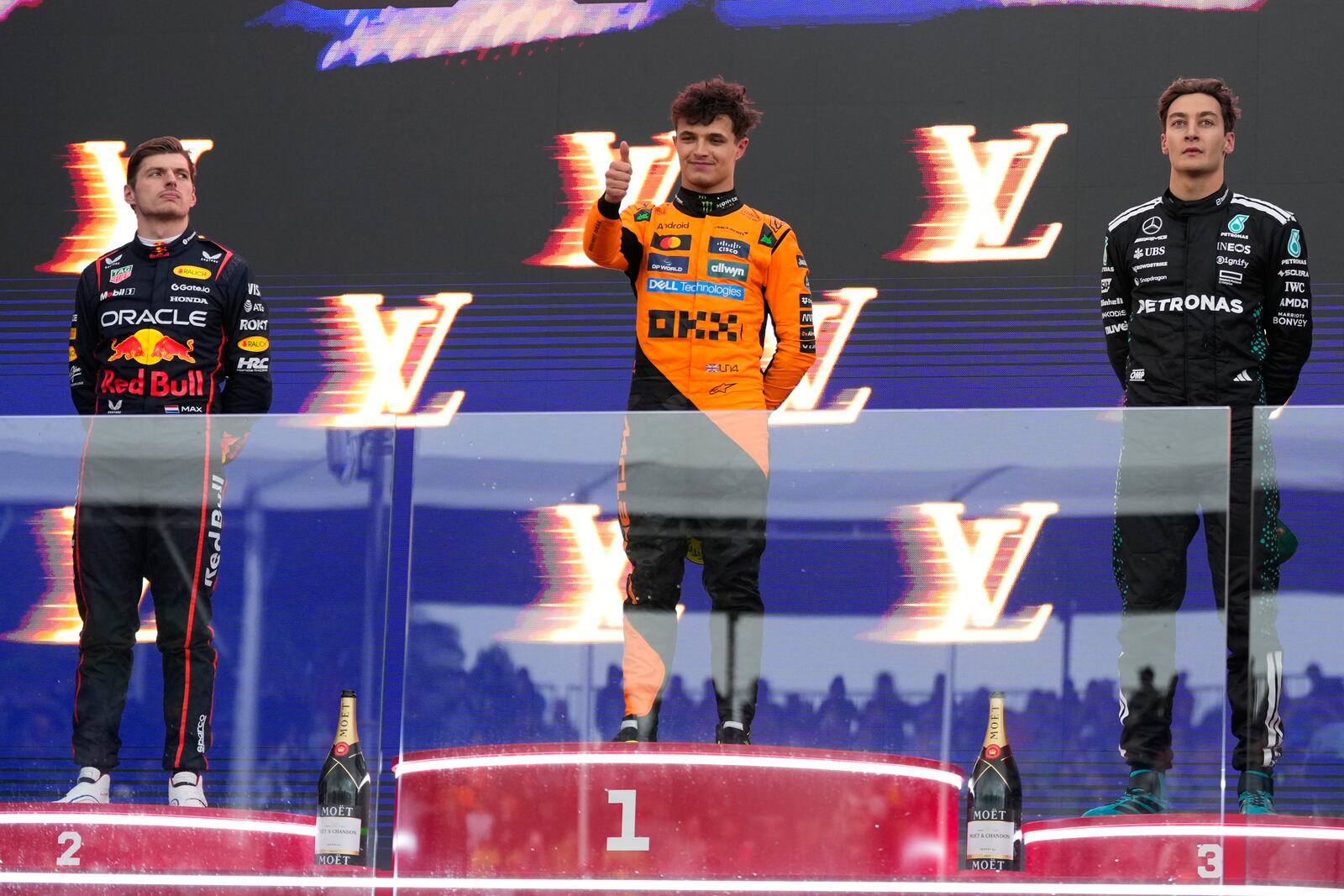 Race winner McLaren driver Lando Norris of Britain, centre, stands with second placed Max Verstappen, left, of the Netherlands and third placed Mercedes driver George Russell, right, of Britain on the podium following the Australian Formula One Grand Prix at Albert Park, in Melbourne, Australia, Sunday, March 16, 2025. (AP Photo/Asanka Brendon Ratnayake)