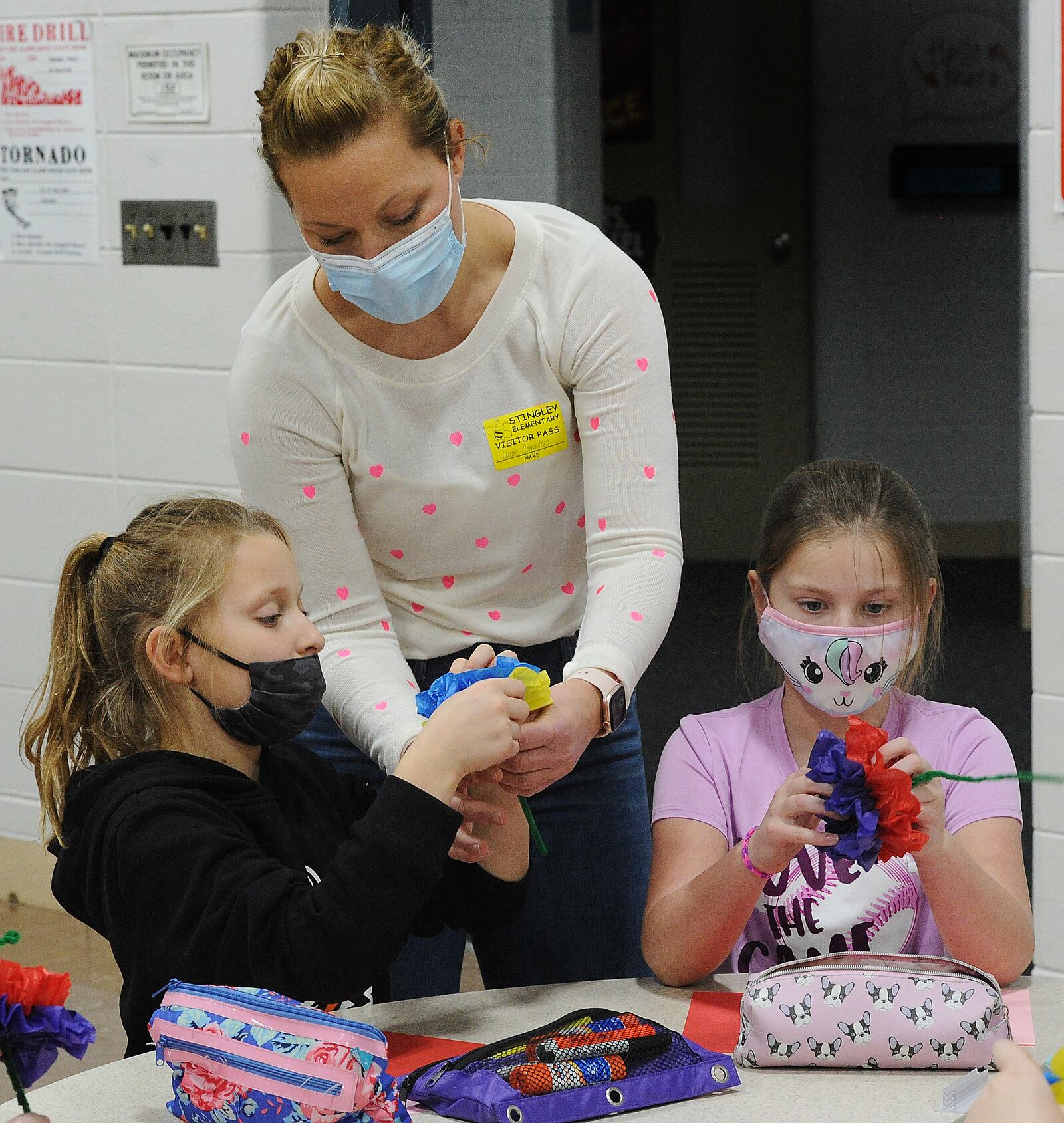 Jamie Compton works with students Cate Compton, left, and Reagan Wilder on making paper flowers for a local nursing home at a Valentine's Day party at Stingley Elementary in Centerville on Friday, Feb. 11, 2022. The PTO is doing a fundraiser where students do acts of kindness in return for donations to the school. MARSHALL GORBY\STAFF