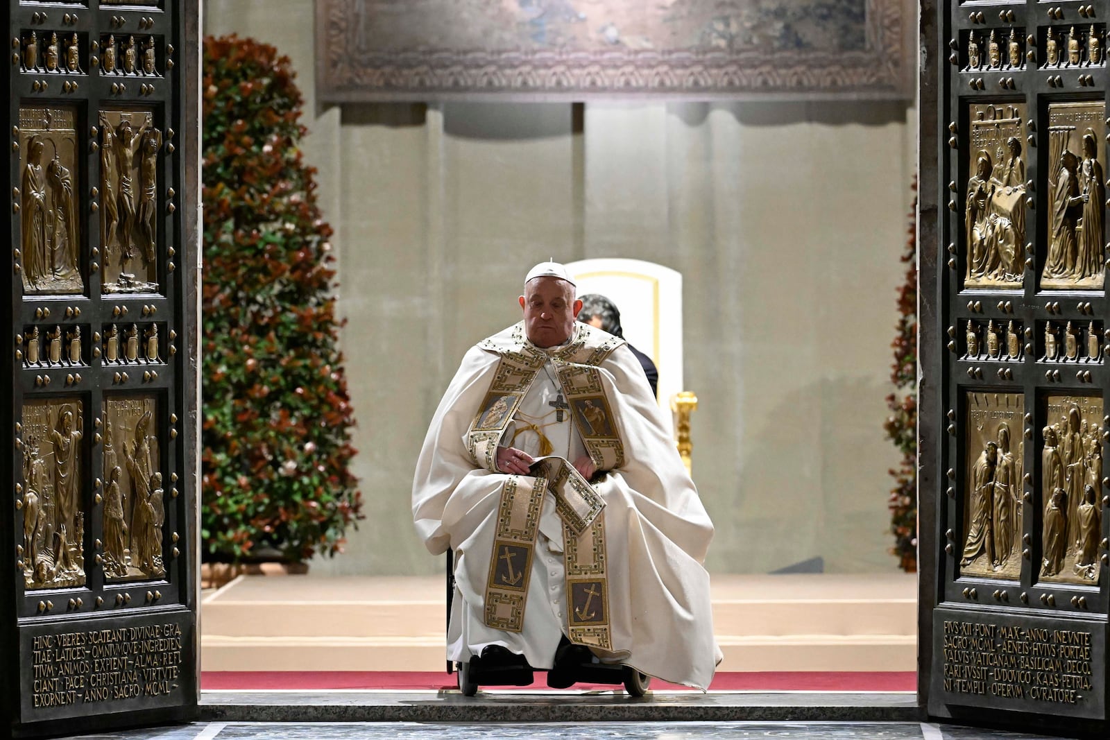 In this image released by Vatican Media, Pope Francis opens the holy door marking the start of the Catholic jubilar year 2025 before presiding over the Christmas Eve Mass in St. Peter's Basilica at The Vatican, Tuesday, Dec. 24, 2024. (AP Photo/Vatican Media, HO)