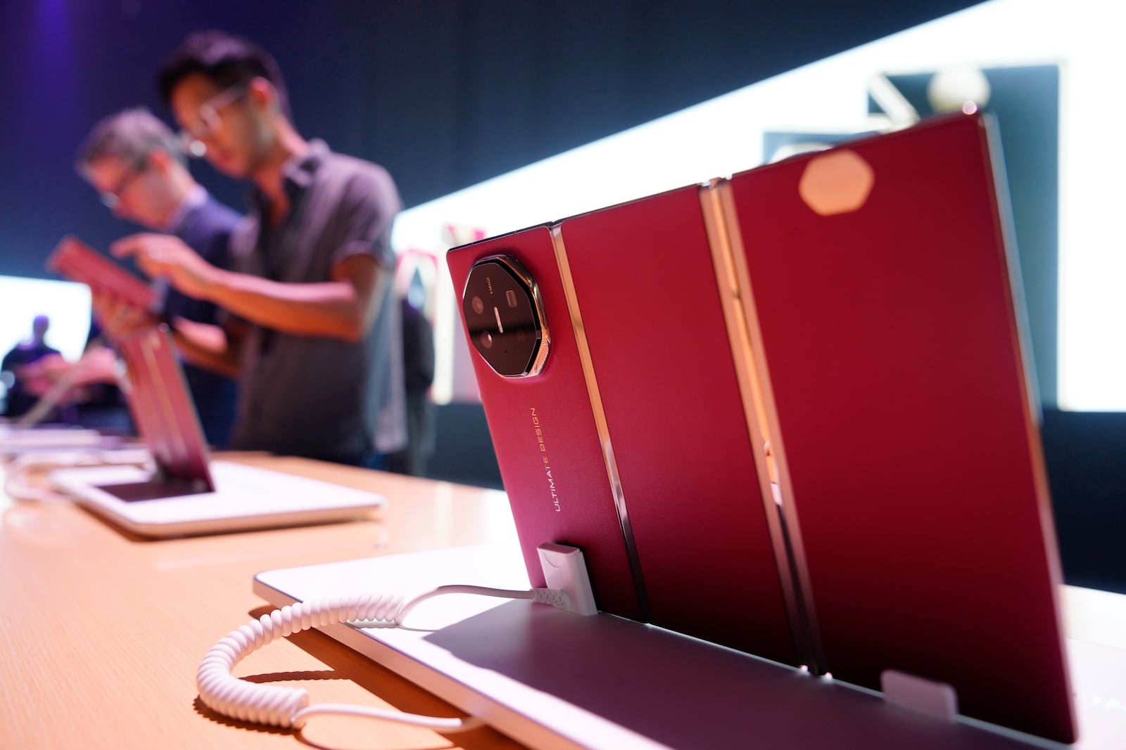 Visitors look at a display during the sales global opening of Huawei's industry's first tri-foldable phone, right, in Kuala Lumpur, Malaysia, Tuesday, Feb. 18, 2025. (AP Photo/Vincent Thian)