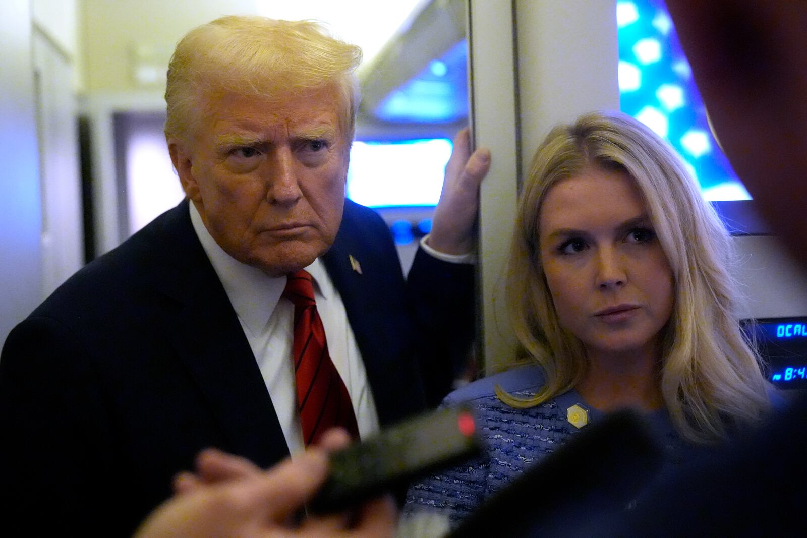 President Donald Trump speaks to reporters aboard Air Force One en route from Miami to Joint Base Andrews, Md., Monday, Jan. 27, 2025, as White House press secretary Karoline Leavitt listens. (AP Photo/Mark Schiefelbein)