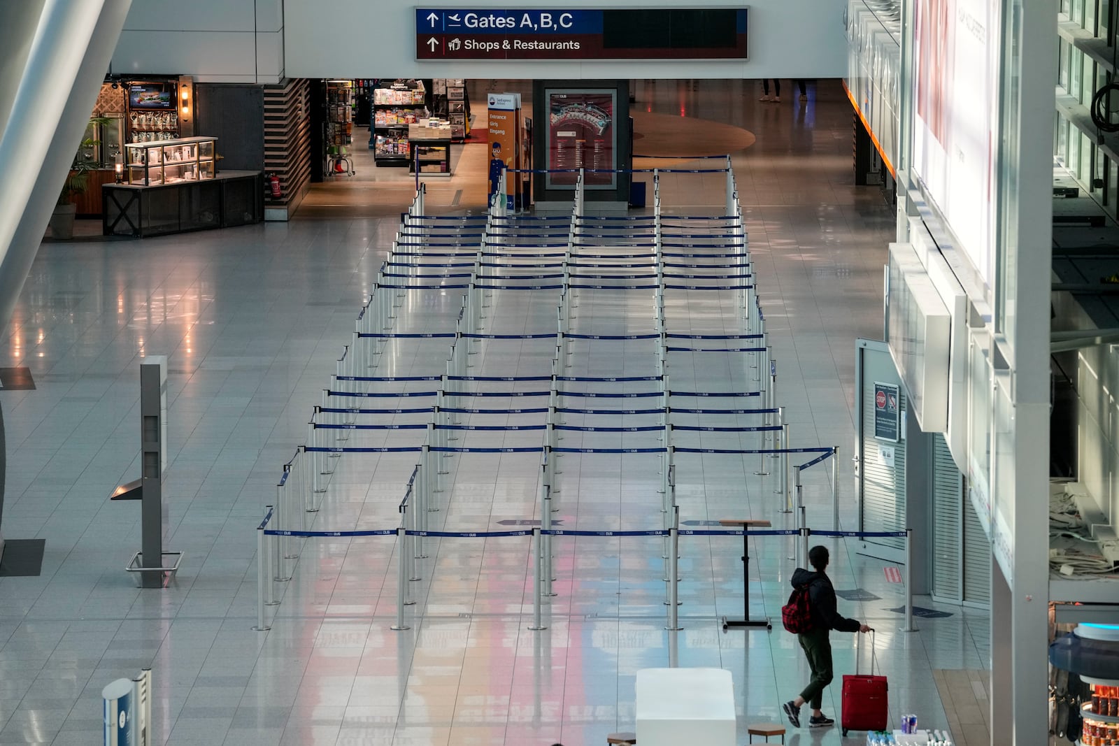 A traveller watches an empty check in at the airport in Duesseldorf, Germany on Monday, March 10, 2025, when all major airports in Germany went on a warning strike. (AP Photo/Martin Meissner)