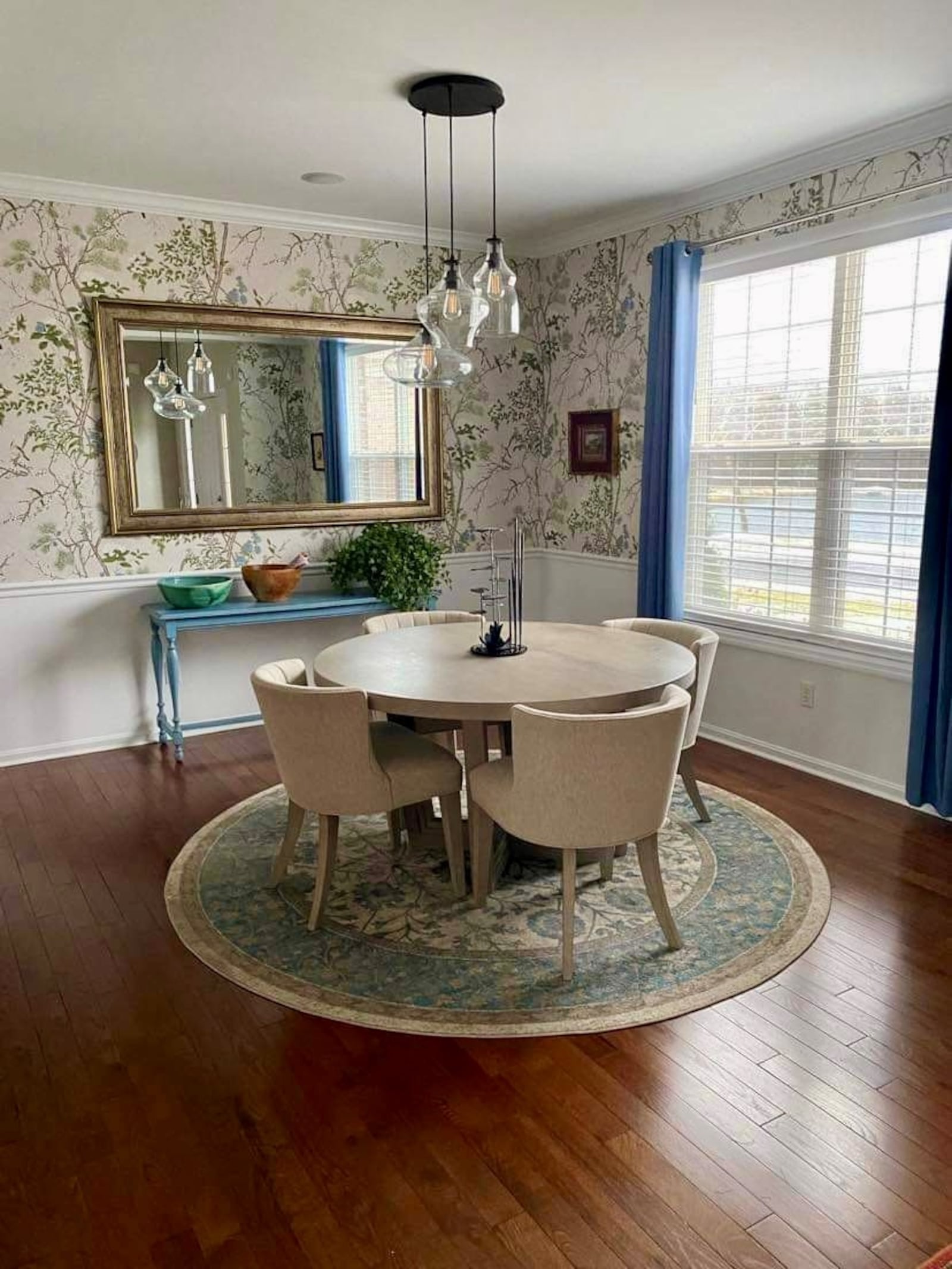 A large gilt mirror and blue drapes finish the dining room, which projects relaxed glamour. 