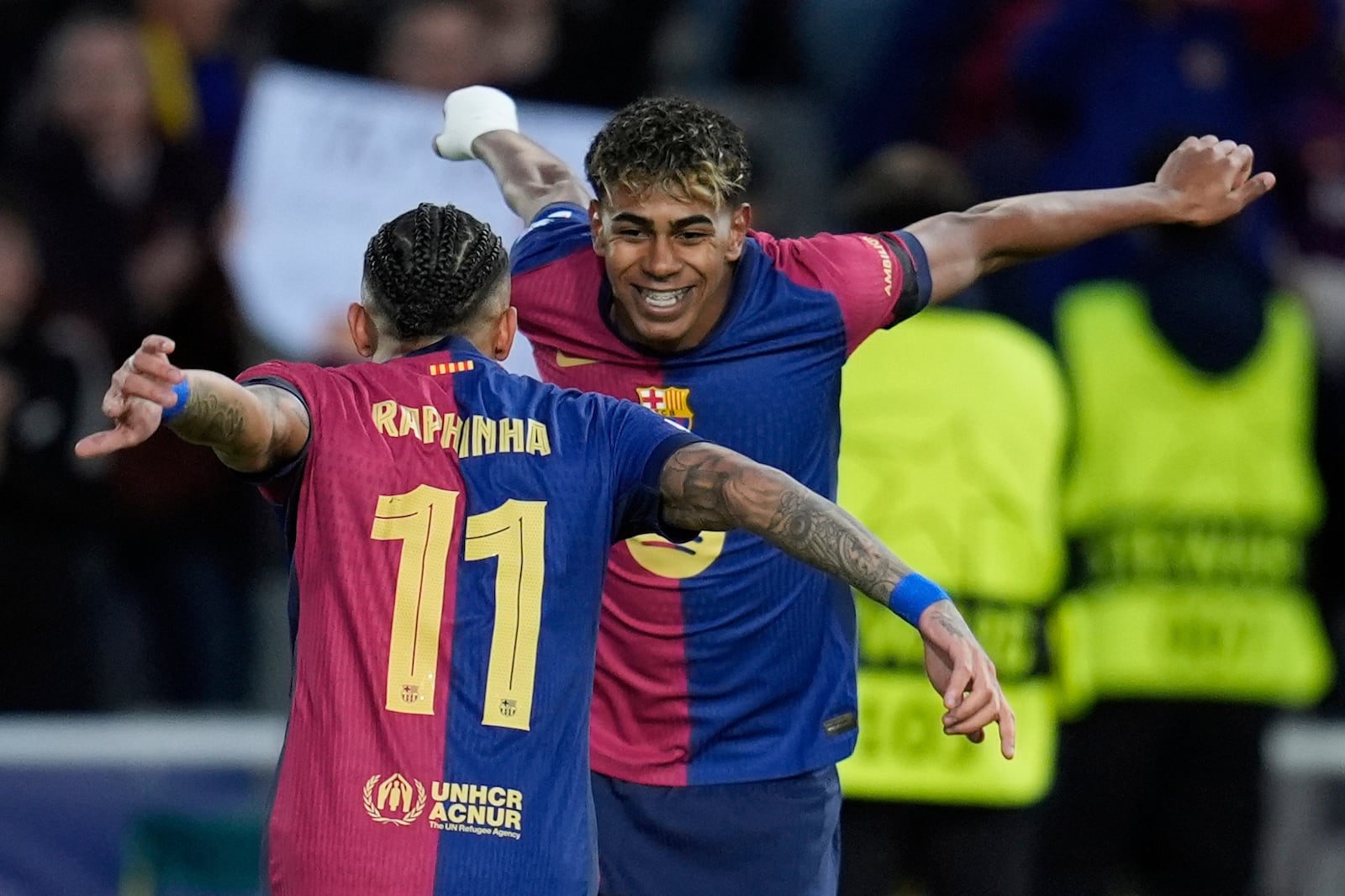 Barcelona's Raphinha, left, celebrates with his teammate Lamine Yamal after scoring his side's opening goal during the Champions League round of 16 second leg soccer match between FC Barcelona and SL Benfica at the Lluis Companys Olympic Stadium in Barcelona, Spain, Tuesday, March 11, 2025. (AP Photo/Emilio Morenatti)