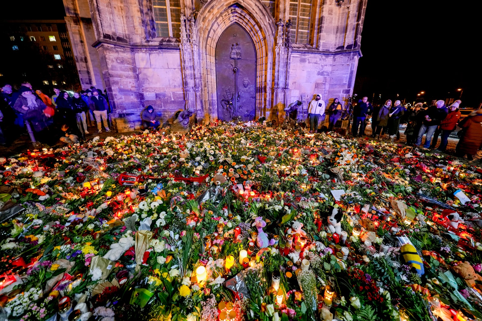 People have laid flowers and candles in front of the Johannis church close to the Christmas market, where a car drove into a crowd on Friday evening, in Magdeburg, Germany, Saturday, Dec. 21, 2024. (AP Photo/Michael Probst)