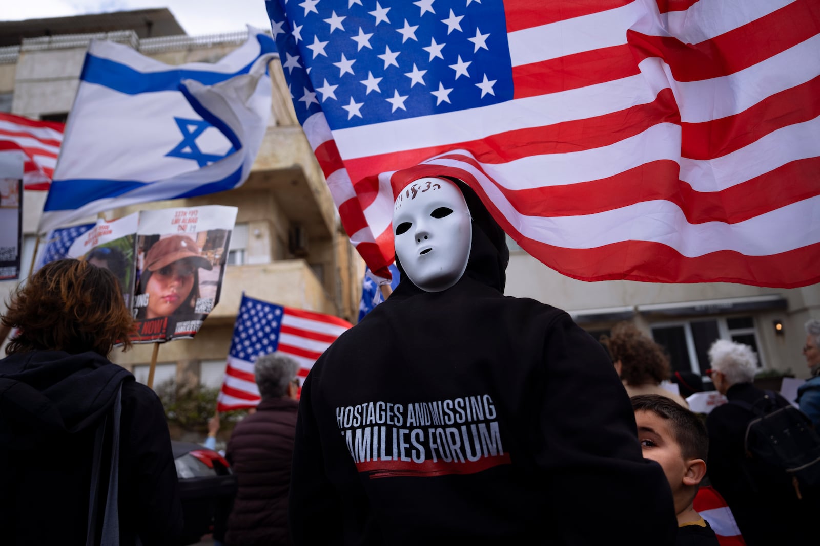 FILE - Families and supporters of Israeli hostages held by Hamas in Gaza wave photos of their loved ones and the Israeli and U.S. flags during a protest calling for their return, outside a meeting between U.S. Secretary of State Antony Blinken and families of hostages, in Tel Aviv, Israel, Friday, March 22, 2024. (AP Photo/Oded Balilty, File)