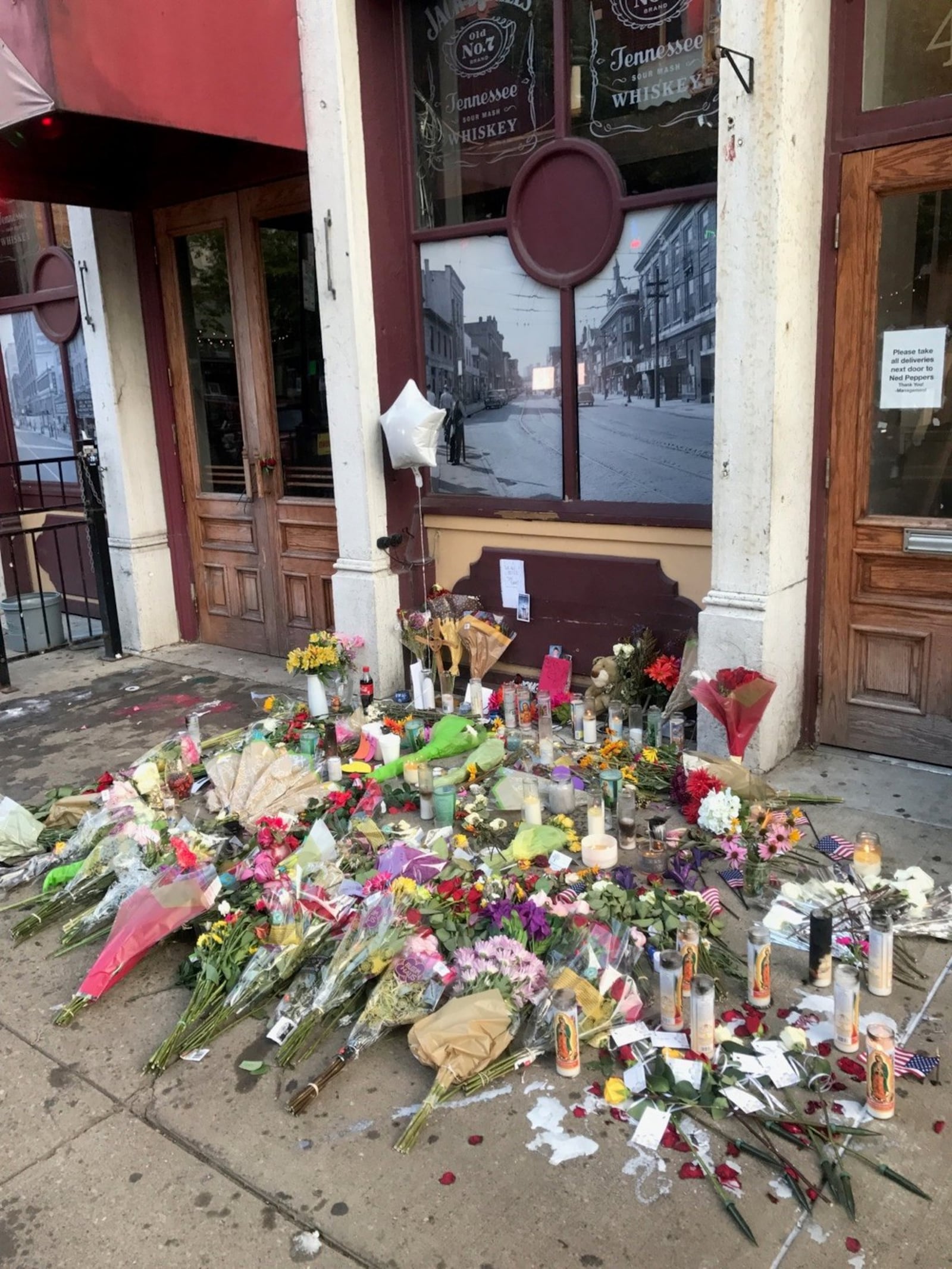 A few hours after the attack in the Oregon District left nine people dead, a memorial began to take shape in front of Ned Peppers bar, where many of the victims died on the sidewalk or street. The remembrances left by people including Mike Turner, the dad of Logan Turner, the slain 30 year old who once played football a Springboro High included a pink covered bible with two photos of a young Logan Turner peeking from the pages and a photo of Logan in his No. 78 Panthers football jersey that remains tape to the iron fencing next to the door of Ned Peppers bar on E. Fifth St. Tom Archdeacon/STAFF