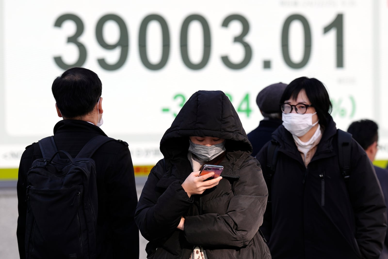 People walk in front of an electronic stock board showing Japan's Nikkei index at a securities firm Wednesday, Dec. 25, 2024, in Tokyo. (AP Photo/Eugene Hoshiko)