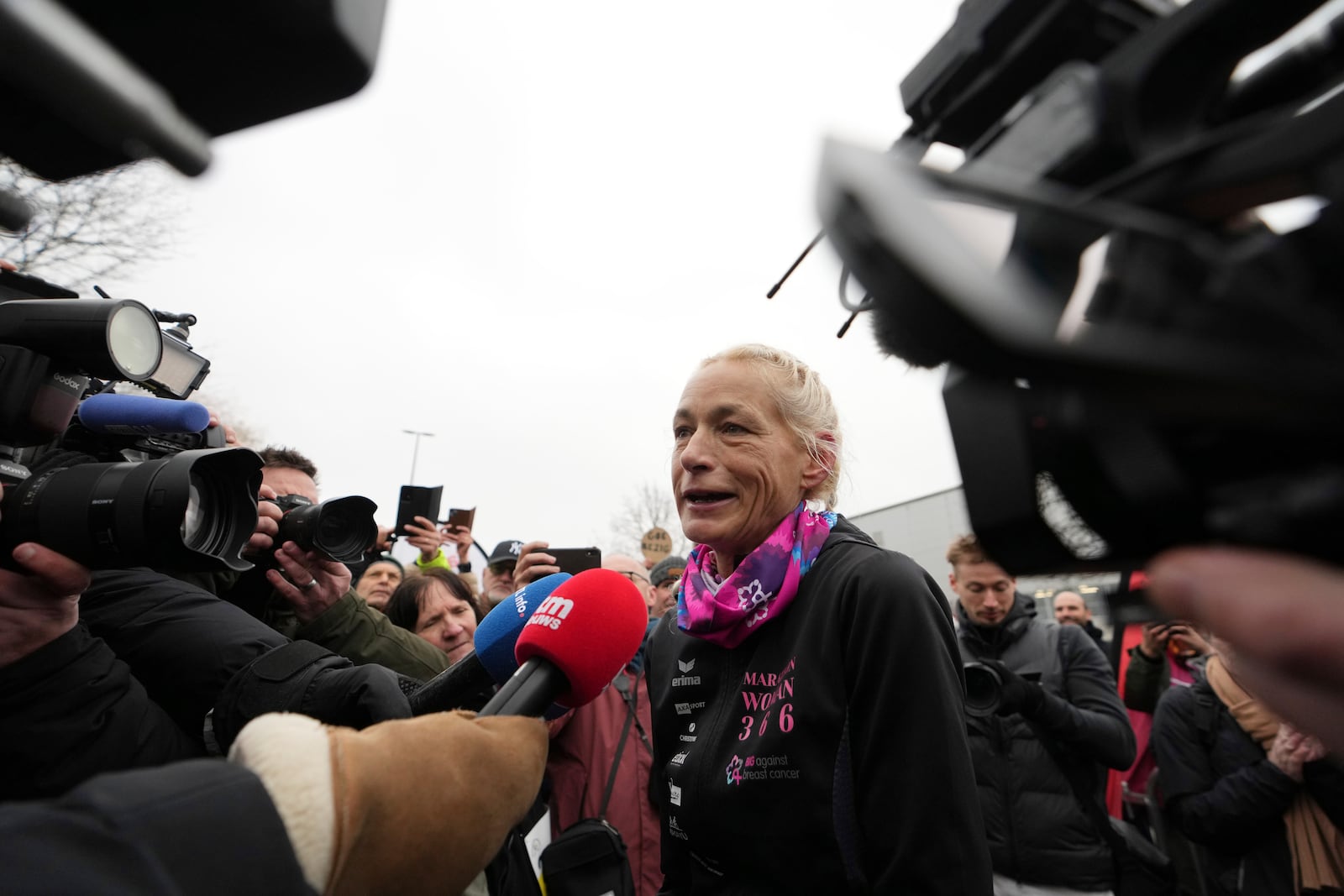 Belgian ultra runner Hilde Dosogne, center, is interviewed after crossing the finish line of her 366th consecutive marathon in Ghent, Belgium, Tuesday, Dec. 31, 2024. (AP Photo/Virginia Mayo)