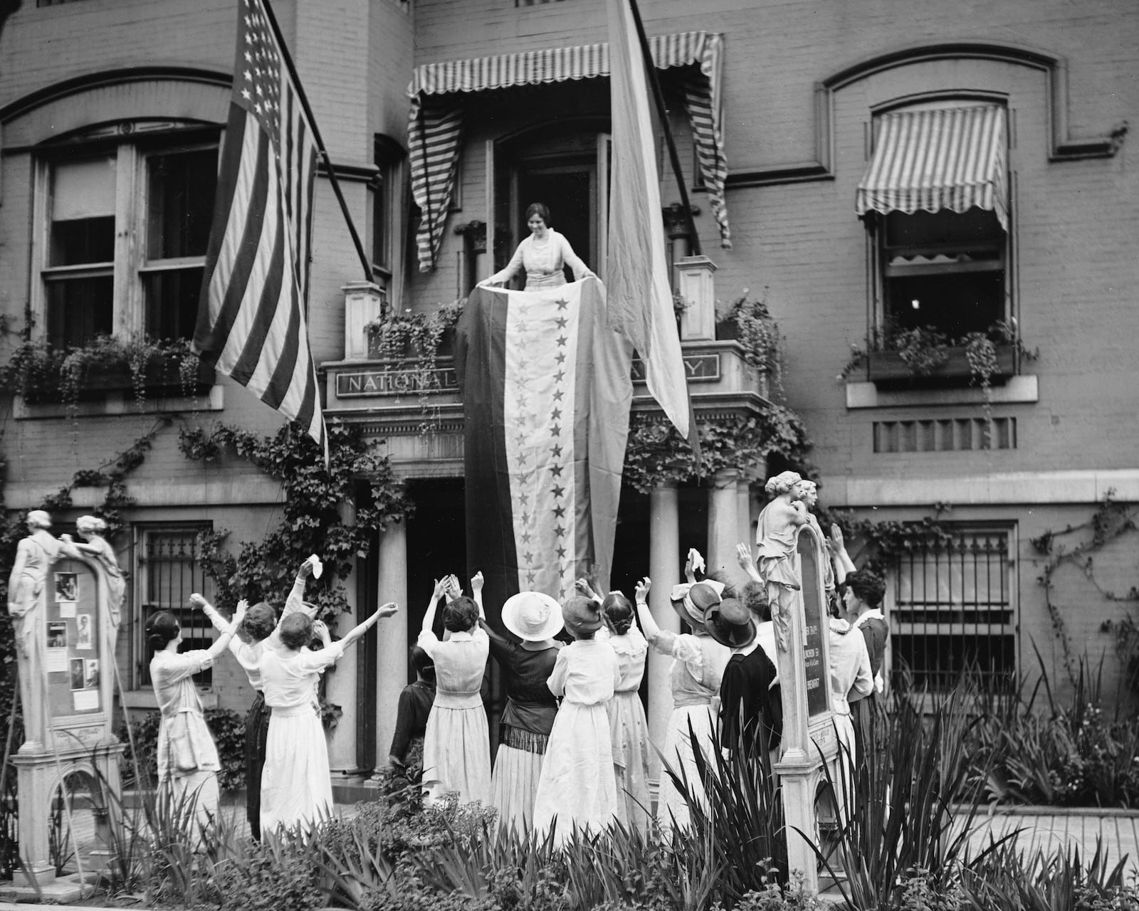 FILE - In this Aug. 19, 1920 photo made available by the Library of Congress, Alice Paul, chair of the National Woman's Party, unfurls a banner after the ratification of the 19th Ammendment, from a balcony at the NWP's headquarters in Washington. (The Crowley Company/Library of Congress via AP, File)