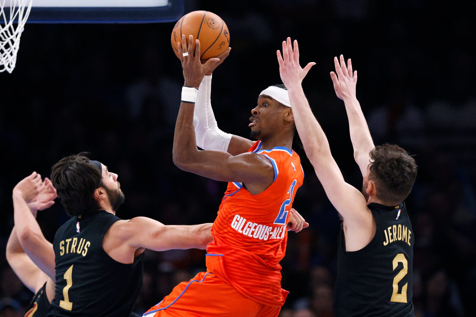 Oklahoma City Thunder guard Shai Gilgeous-Alexander, center, looks to pass the ball away from Cleveland Cavaliers guards Max Strus, left, and Ty Jerome, right, during the second half of an NBA basketball game Thursday, Jan. 16, 2025, in Oklahoma City. (AP Photo/Nate Billings)