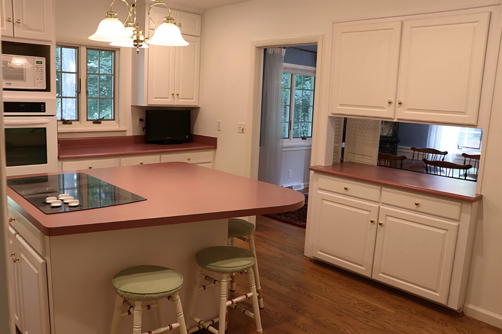 Bi-fold louver doors next to the buffet in the dining room open into the kitchen.  An island has seating, storage and a glass cooktop. White cabinetry fills nearly every wall space and includes two pantries that flank a planning desk. CONTRIBUTED PHOTO BY KATHY TYLER