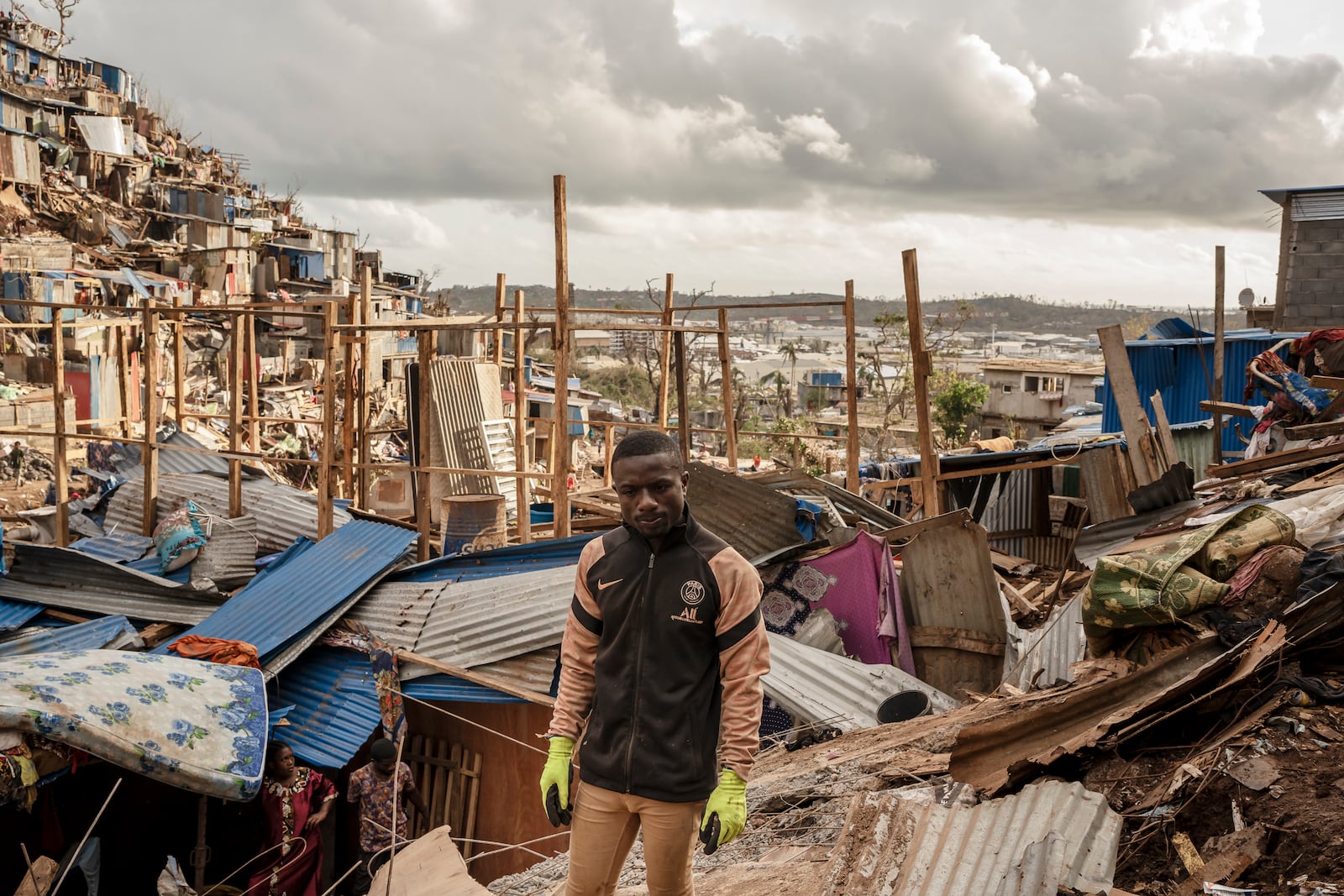 Nassirou Hamidouni, 28, father of five, stands amongst the debris of the neighboring destroyed home in the slum of Kaweni on the outskirts of Mamoudzou, in the French Indian Ocean island of Mayotte Thursday, Dec. 19, 2024, after Cyclone Chido. (AP Photo/Adrienne Surprenant)