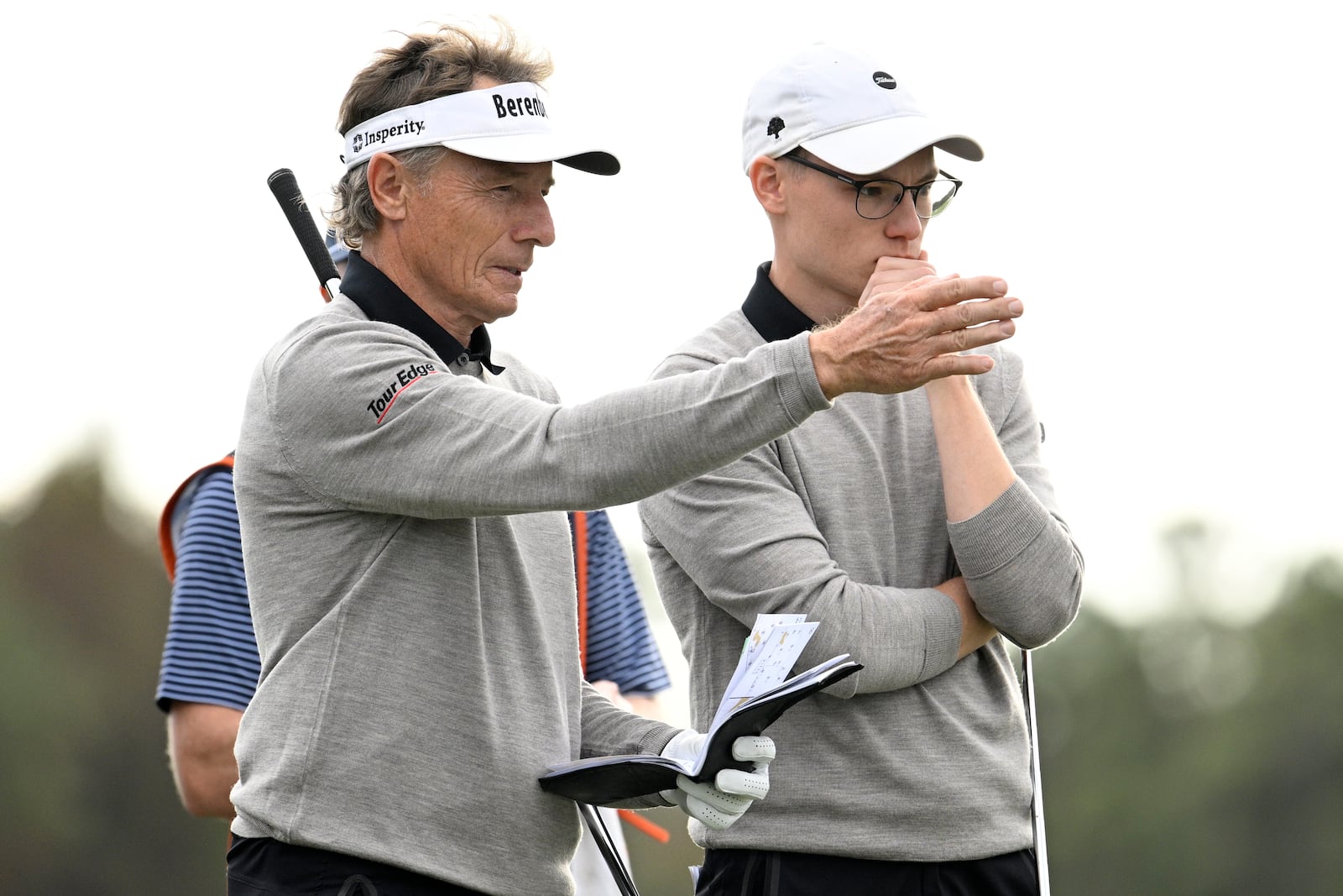 Bernhard Langer, left, and his son Jason Langer, right, discuss their shots before putting on the 14th green during the final round of the PNC Championship golf tournament, Sunday, Dec. 22, 2024, in Orlando, Fla. (AP Photo/Phelan M. Ebenhack)