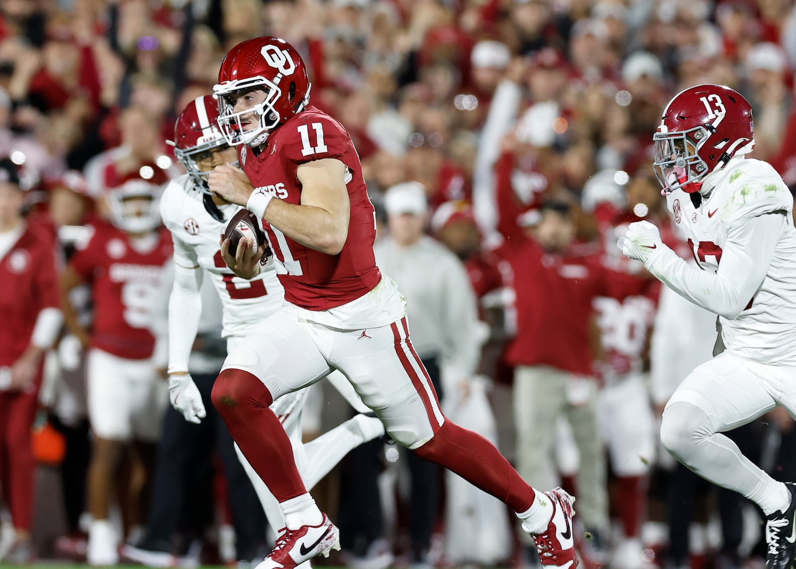 Oklahoma quarterback Jackson Arnold (11) runs for a first down ahead of Alabama defensive back Malachi Moore (13) during the first quarter of a NCAA college football game Saturday, Nov. 23, 2024, in Norman, Okla. (AP Photo/Alonzo Adams)