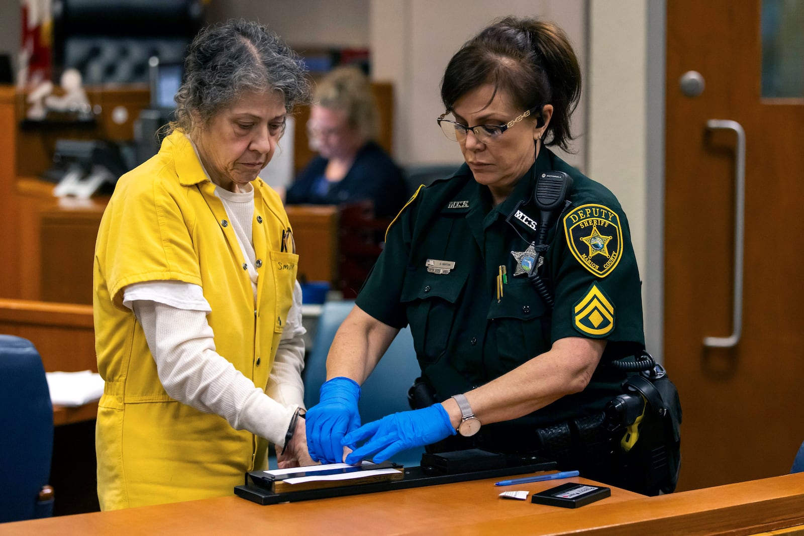 Susan Lorincz, left, who fatally shot a Black neighbor through her front door during an ongoing dispute, is finger printed after she was sentenced to 25 years in prison at a court hearing Monday, Nov. 25, 2024, in Ocala, Fla. (Doug Engle/Ocala Star-Banner via AP, Pool)