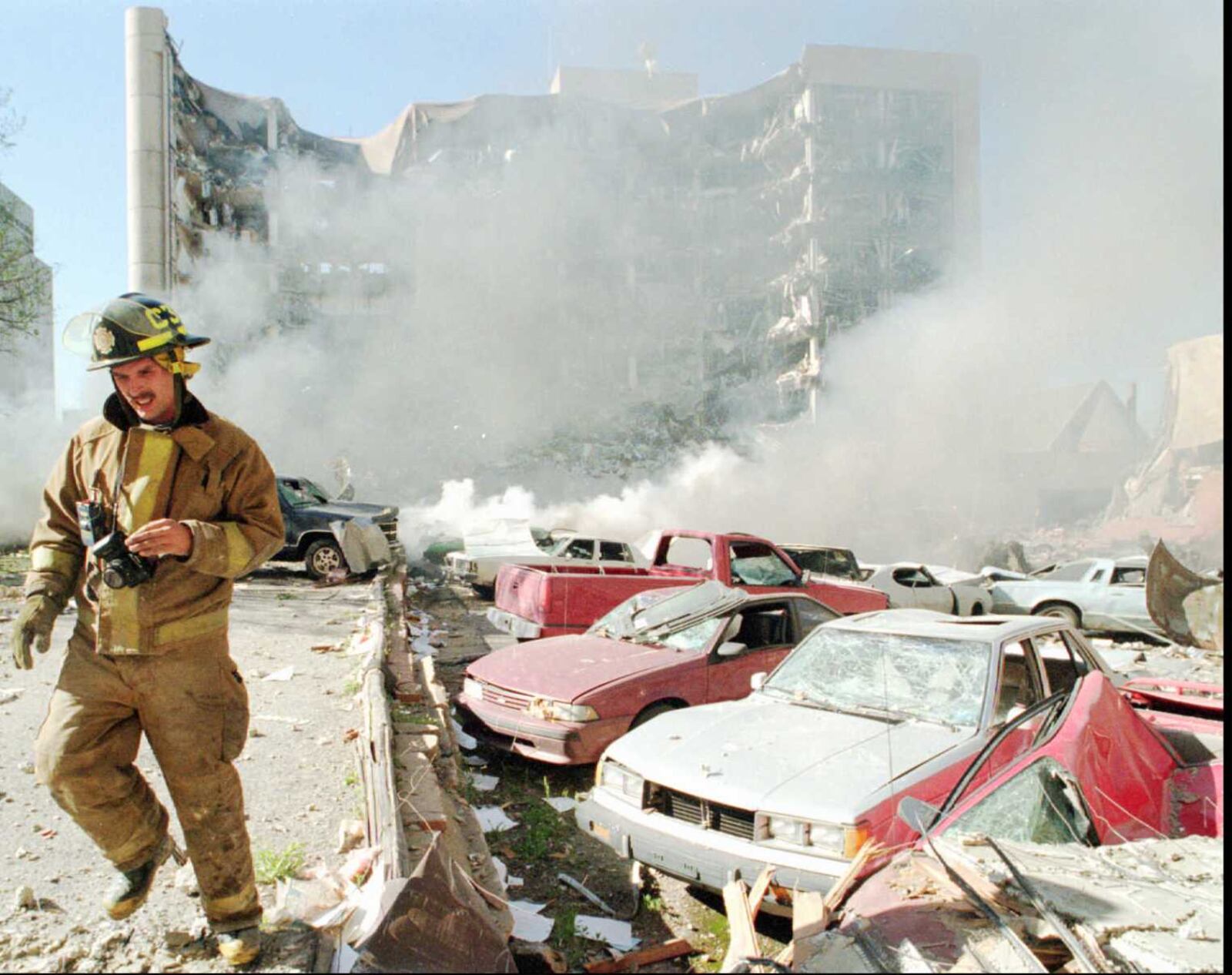 An Oklahoma City fireman walks near explosion damaged cars on the north side of the Alfred Murrah Federal Building in Oklahoma City after a car bomb blast Wednesday April 19 1995 More than 20 people were killed and another 300 were missing in the explosion that gouged a nine story hole in the federal office building (AP Photo / The Daily Oklahoman /Jim Argo)