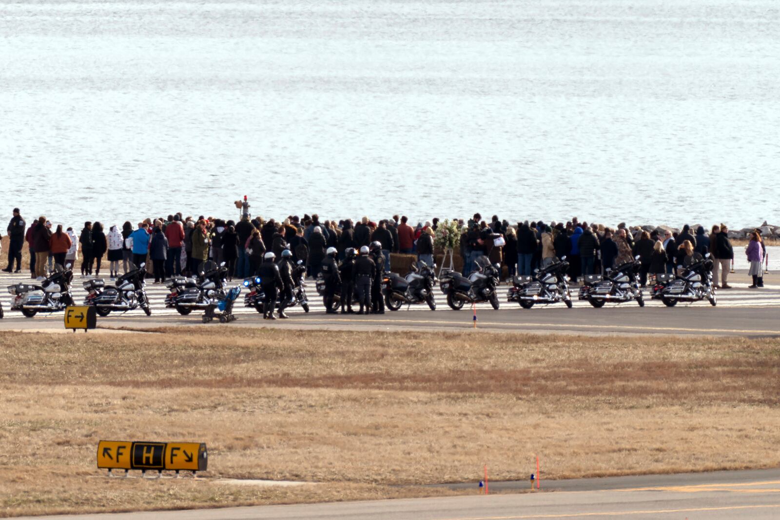 Families of the victims of a mid-air collision between an American Airlines jet and an Army helicopter stand near the wreckage site in the Potomac River at the end of the runway 33 from Ronald Reagan Washington National Airport, Sunday, Feb. 2, 2025, in Arlington, Va. (AP Photo/Jose Luis Magana)