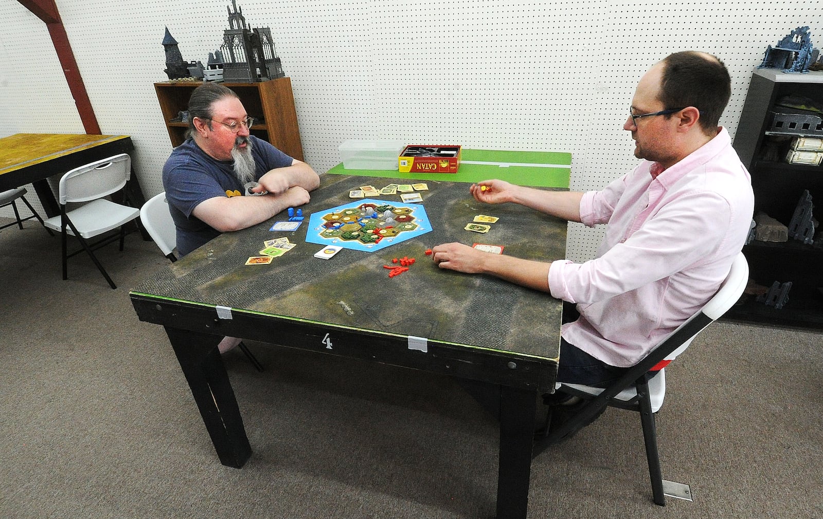 Andrew Coen, co-owner of Bookery Games, left, and Taylor Buckles, co-owner of Bookery Games in Fairborn, play a board game at the store.  MARSHALL GORBY\STAFF