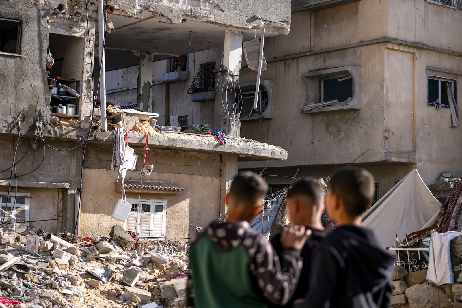 Palestinians look at a damaged residential building following an overnight Israeli strike in Deir al-Balah, Gaza Strip, Wednesday, Jan. 8, 2025. (AP Photo/Abdel Kareem Hana)