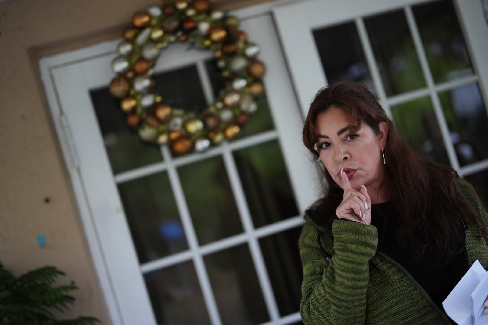 Nora Sandigo, who runs a non-profit dedicated to supporting immigrant families, advises that only one person should respond through a door while others remain quiet, as she role plays how migrants can respond to ICE agents knocking on their door, during a meeting to educate undocumented migrants on their legal rights and options to prepare their families in case a parent were to be detained or deported, Friday, Jan. 17, 2025, in Homestead, Fla. (AP Photo/Rebecca Blackwell)