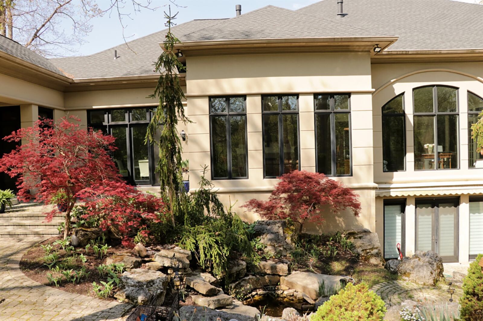 A veranda has views of the 1.7-acre wooded property. The veranda is accessible from the main bedroom suite and a sunroom. The full, finished walk-out lower level opens out to several paver-brick patios and water feature among rocks and landscaping. CONTRIBUTED PHOTO BY KATHY TYLER